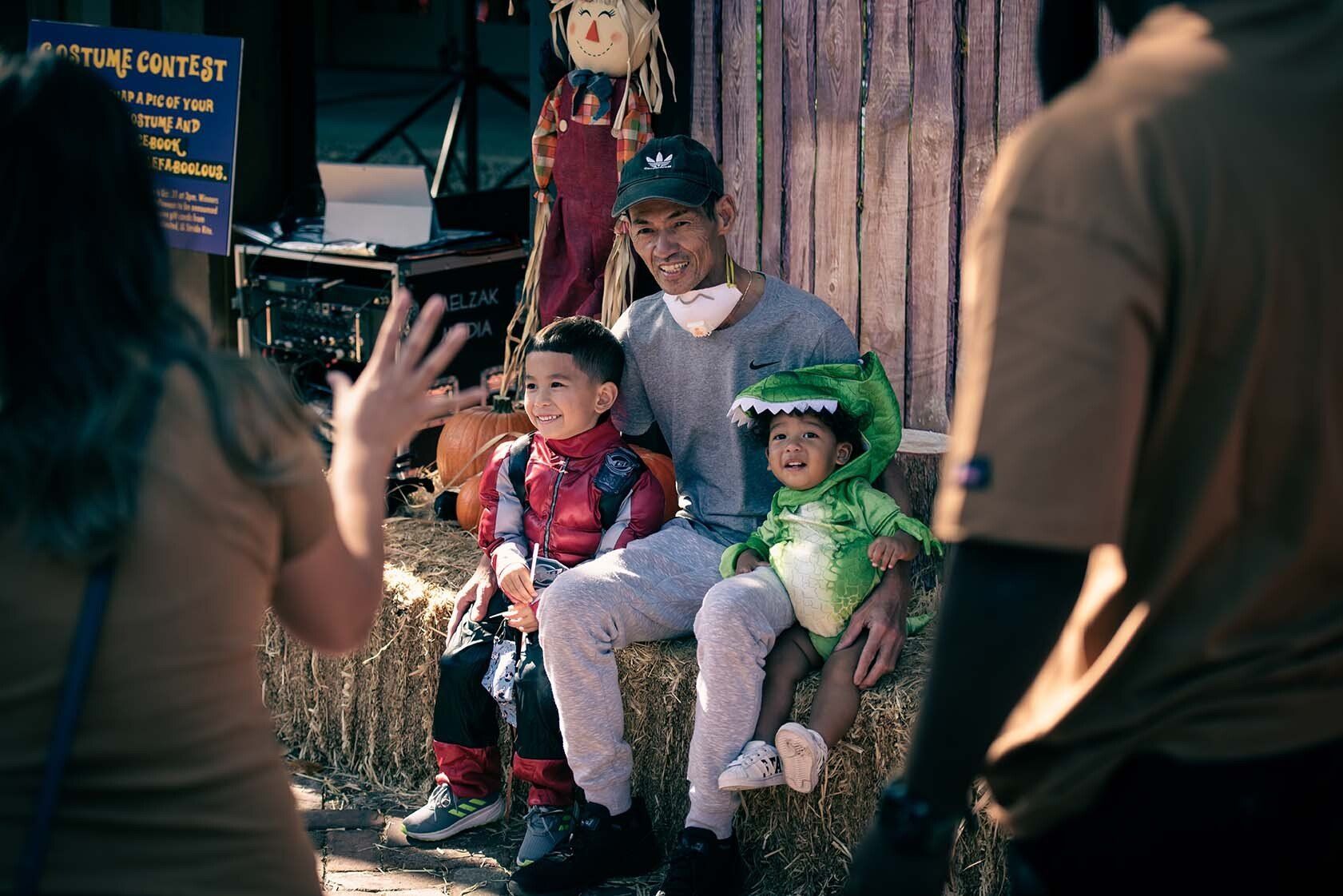 A man and two children are sitting on a bale of hay.