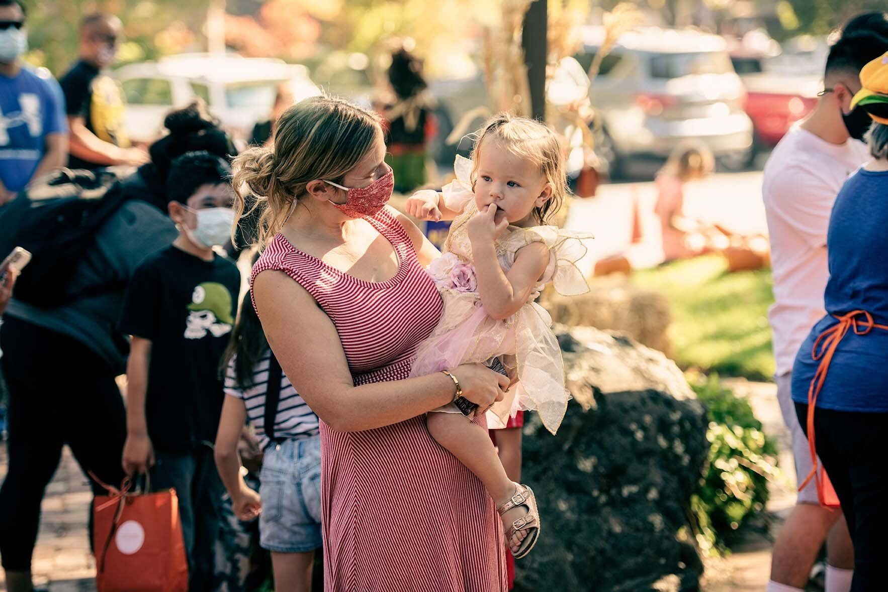 A woman is holding a little girl in her arms while wearing a mask.