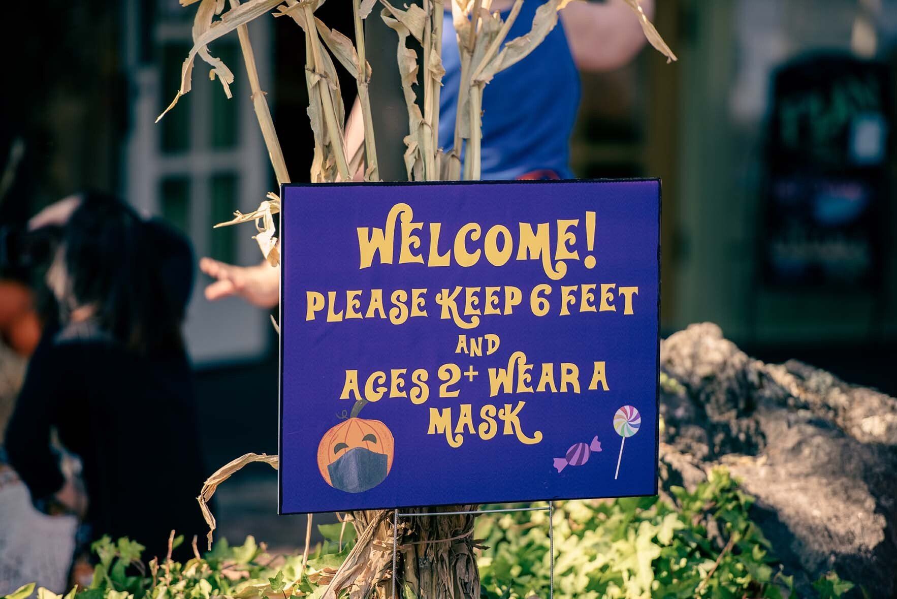 A sign that says welcome please keep 6 feet and ages 2 wear a mask