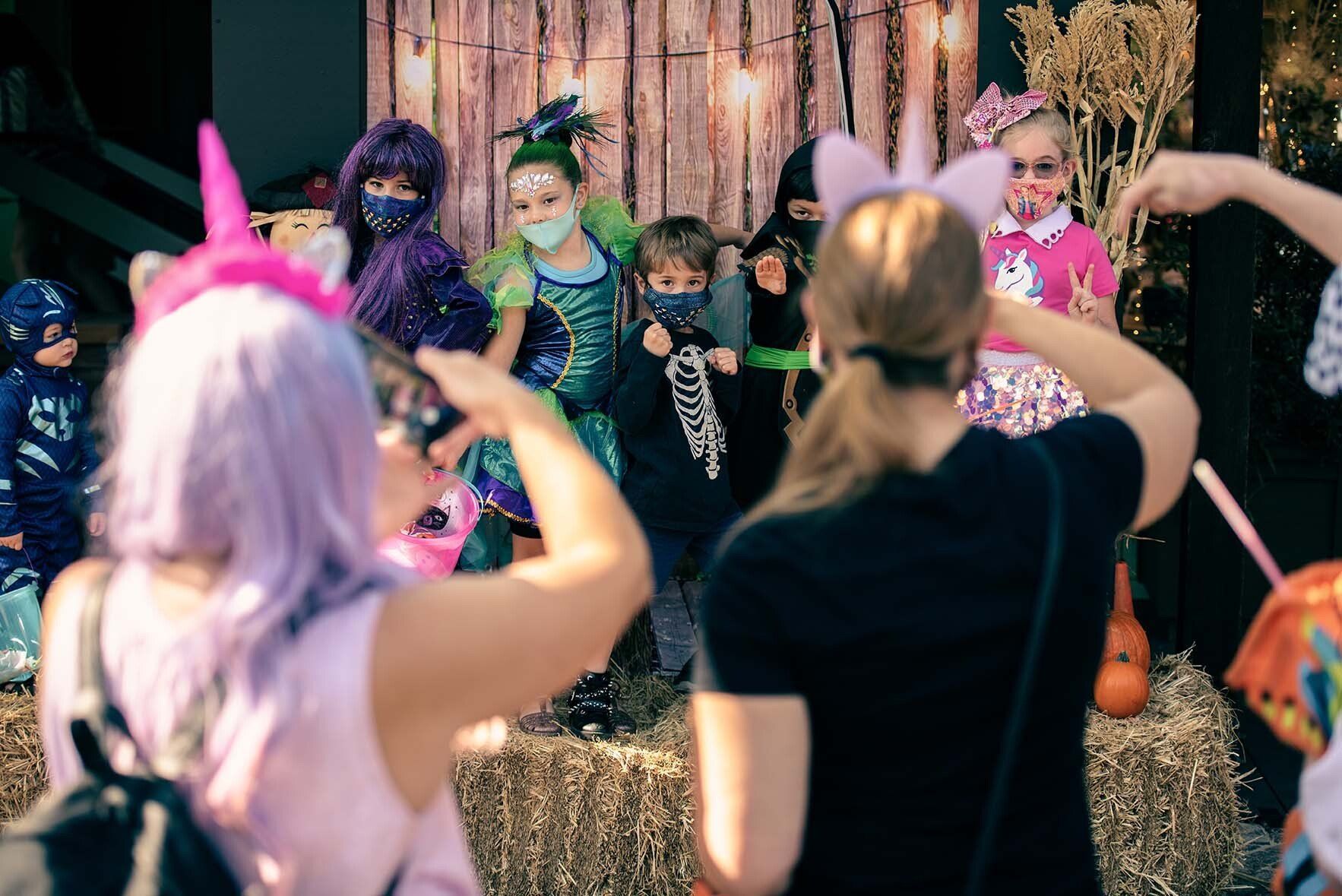 A woman is taking a picture of a group of children in costumes.