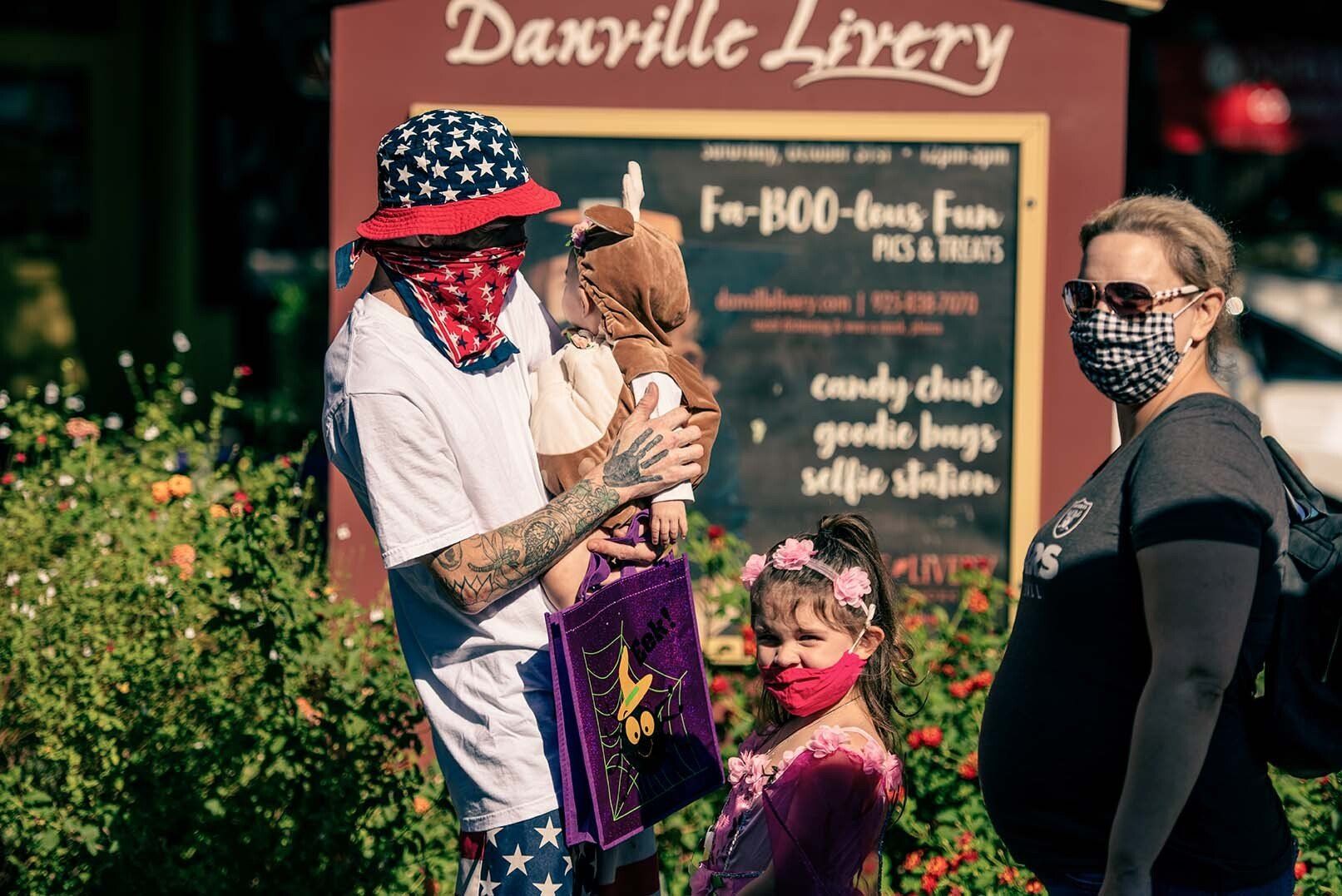 A group of people wearing face masks are standing in front of a sign.