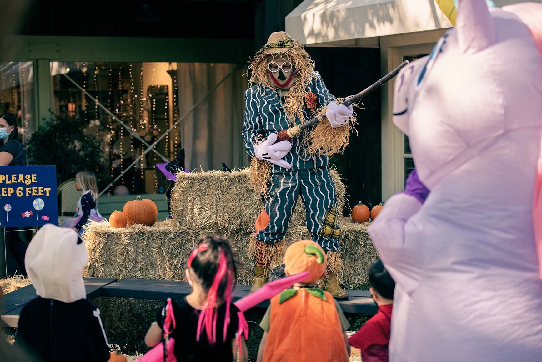A scarecrow is standing in front of a sign that says please be quiet.