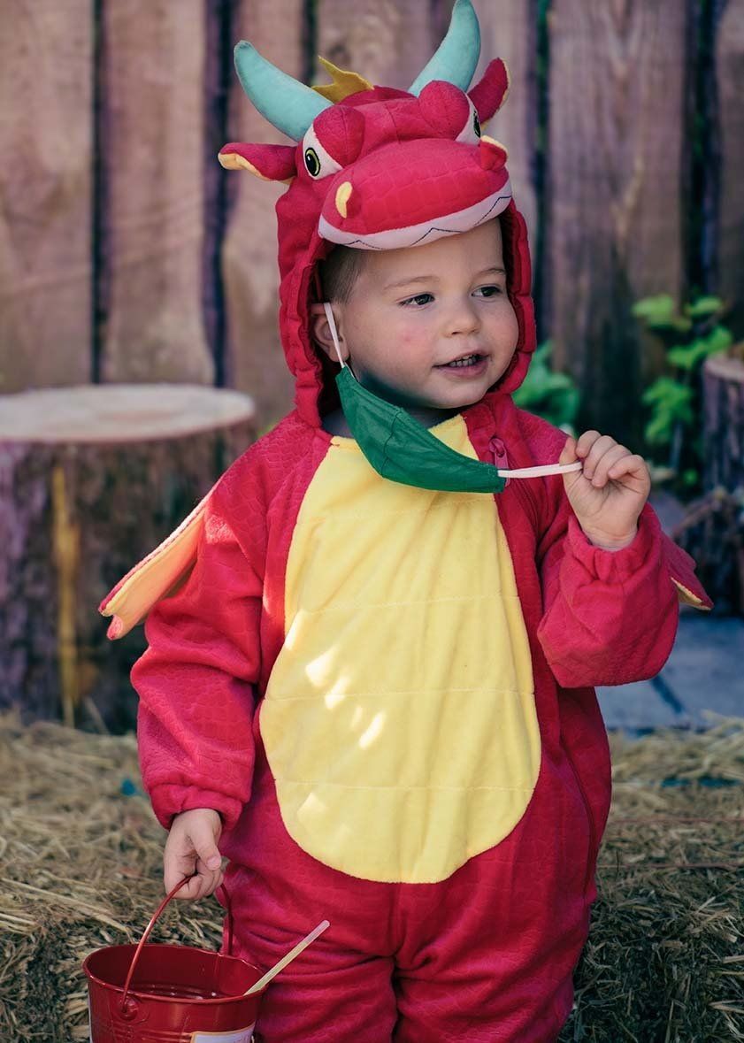 A baby in a dragon costume is holding a lollipop.