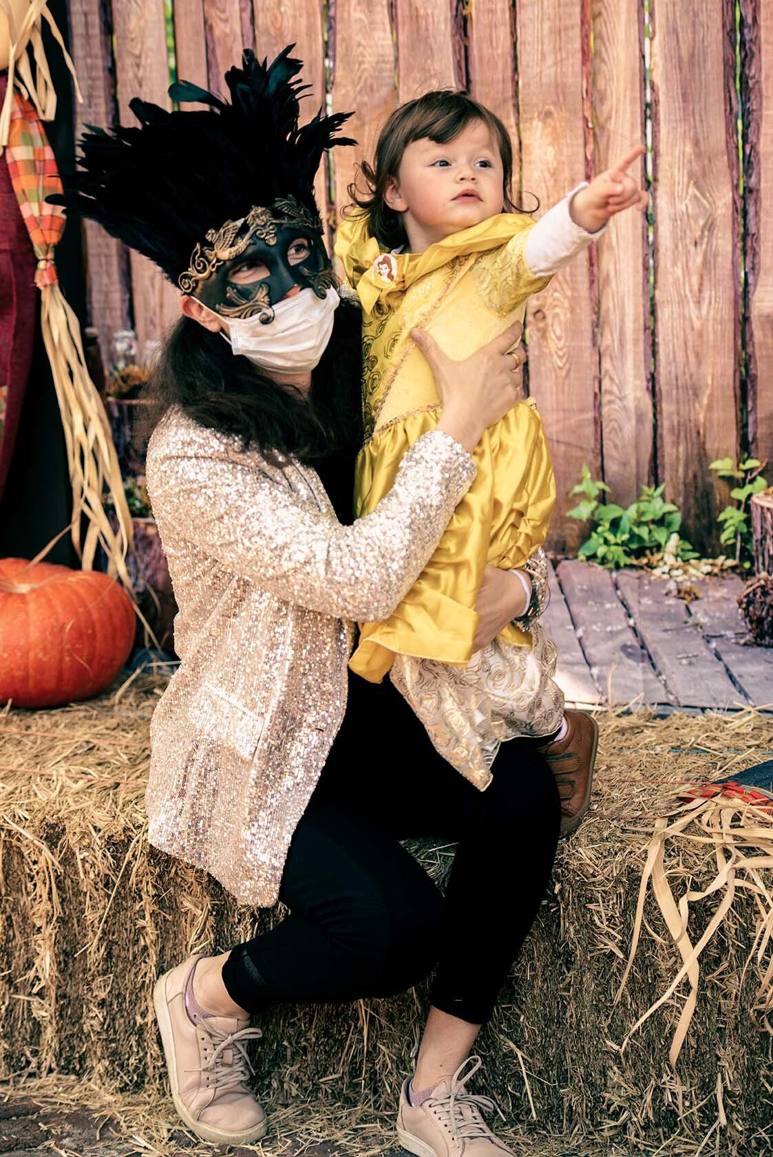 A woman wearing a mask is holding a little girl in her arms.