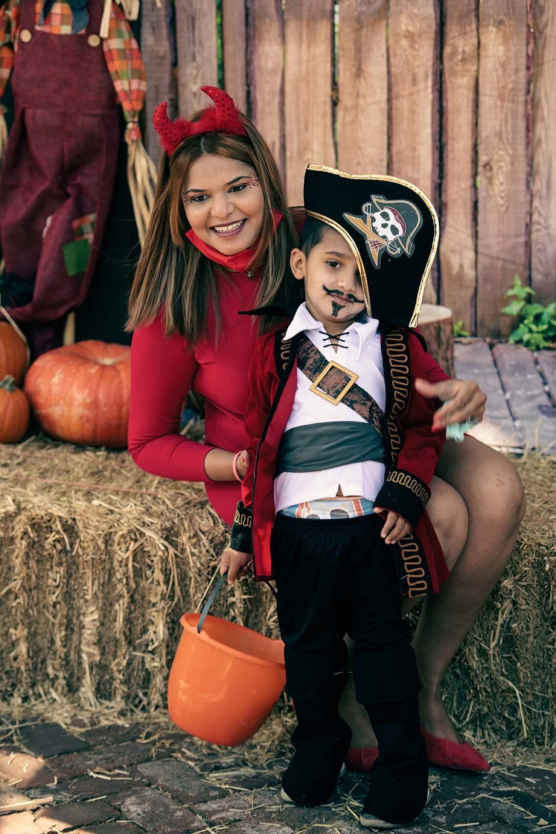 A woman is sitting next to a little boy in a pirate costume.
