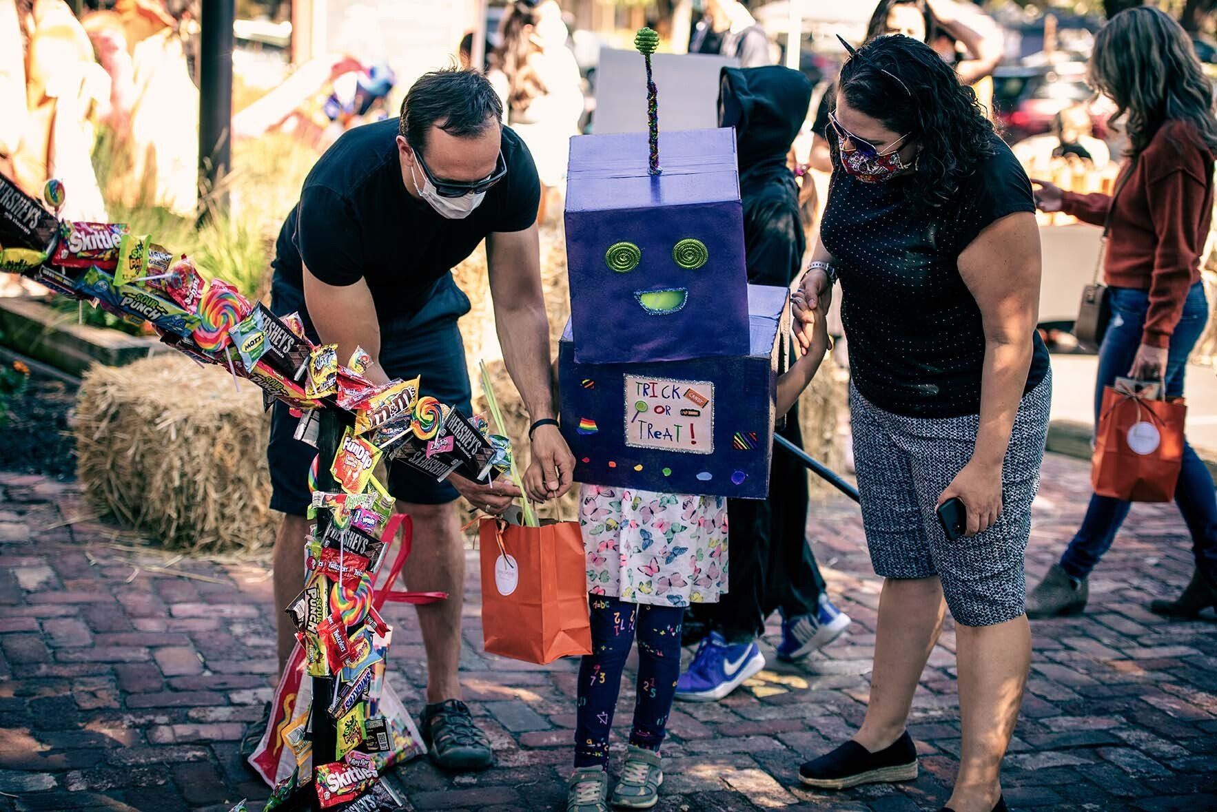 A man and a woman are standing next to a child dressed as a robot.