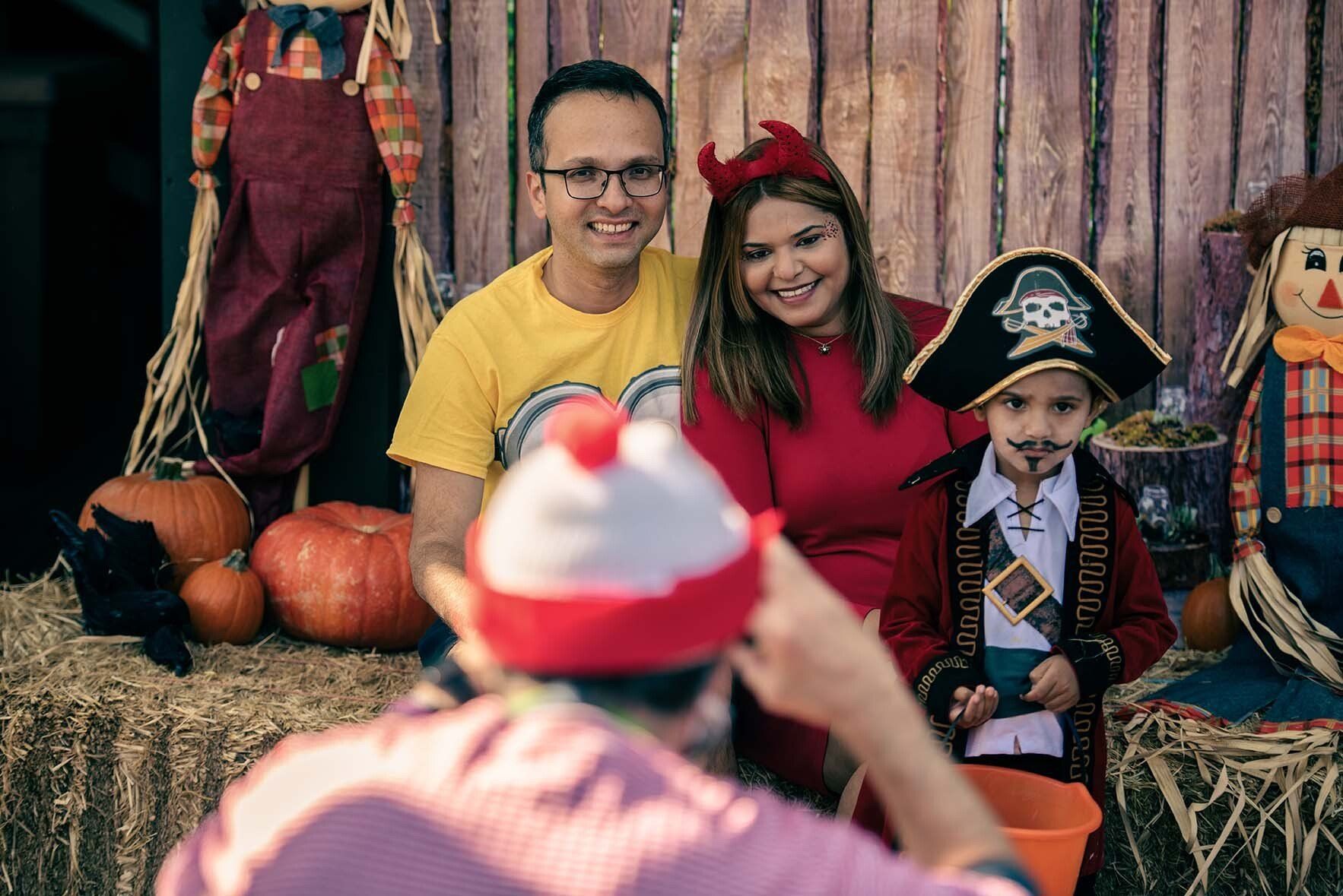 A man is taking a picture of a family in halloween costumes.