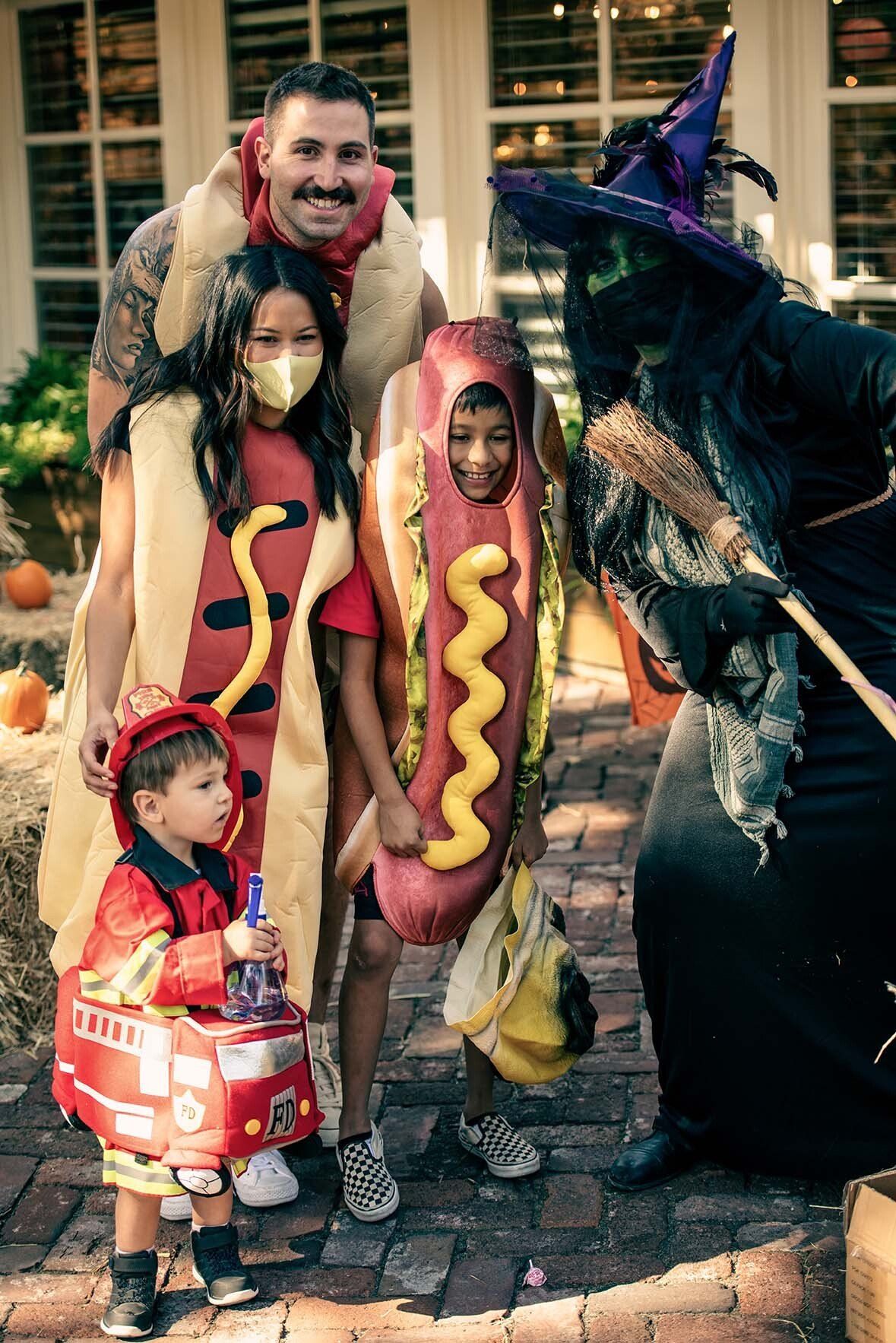 A group of people dressed in halloween costumes are posing for a picture with a witch.