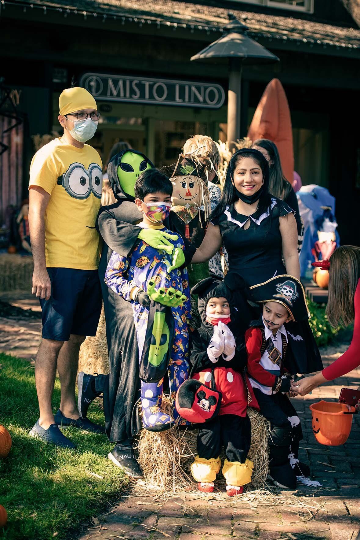 A family is posing for a picture at a halloween trick or treat event.