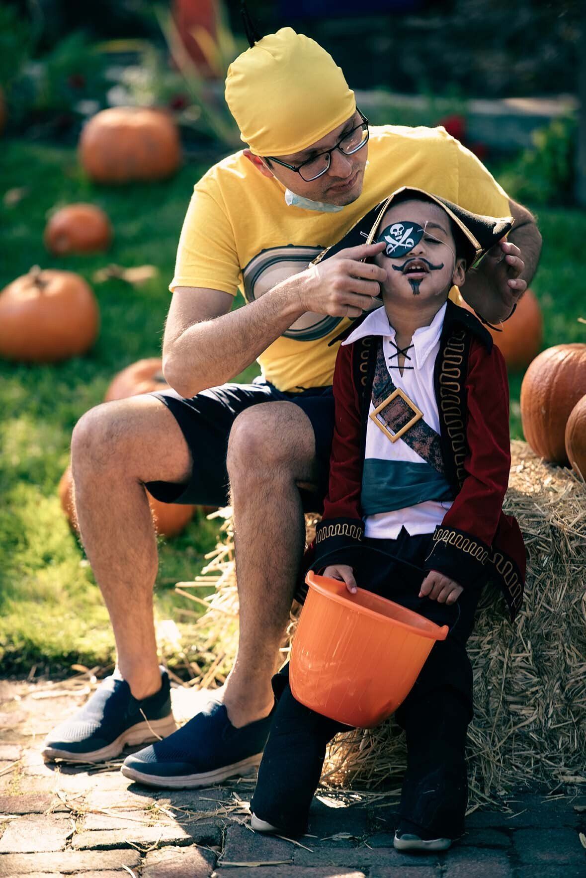 A man is sitting next to a little boy in a pirate costume.