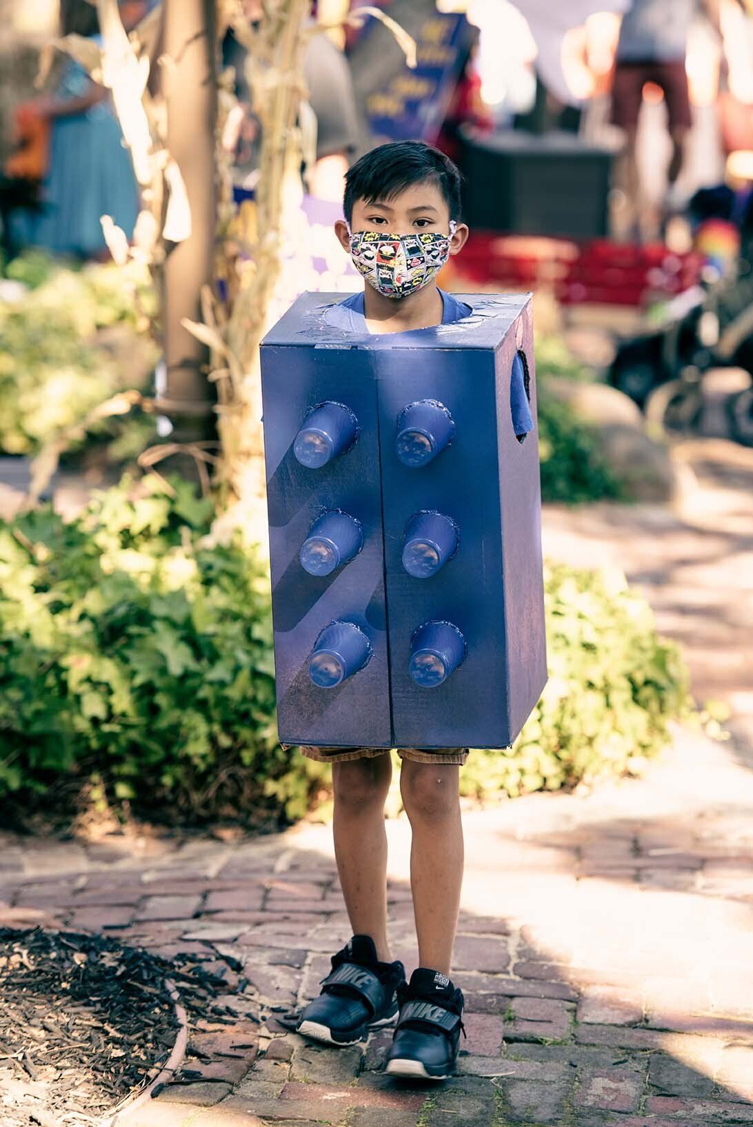 A young boy is wearing a mask and a lego costume.