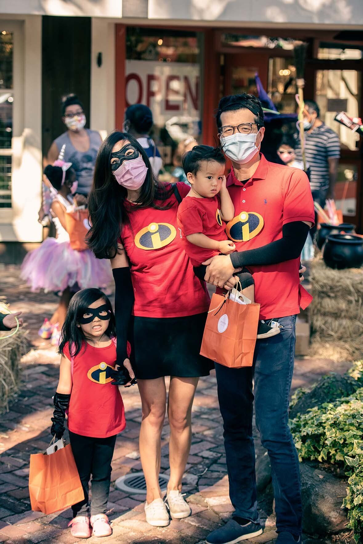 A family is standing next to each other wearing masks and costumes.