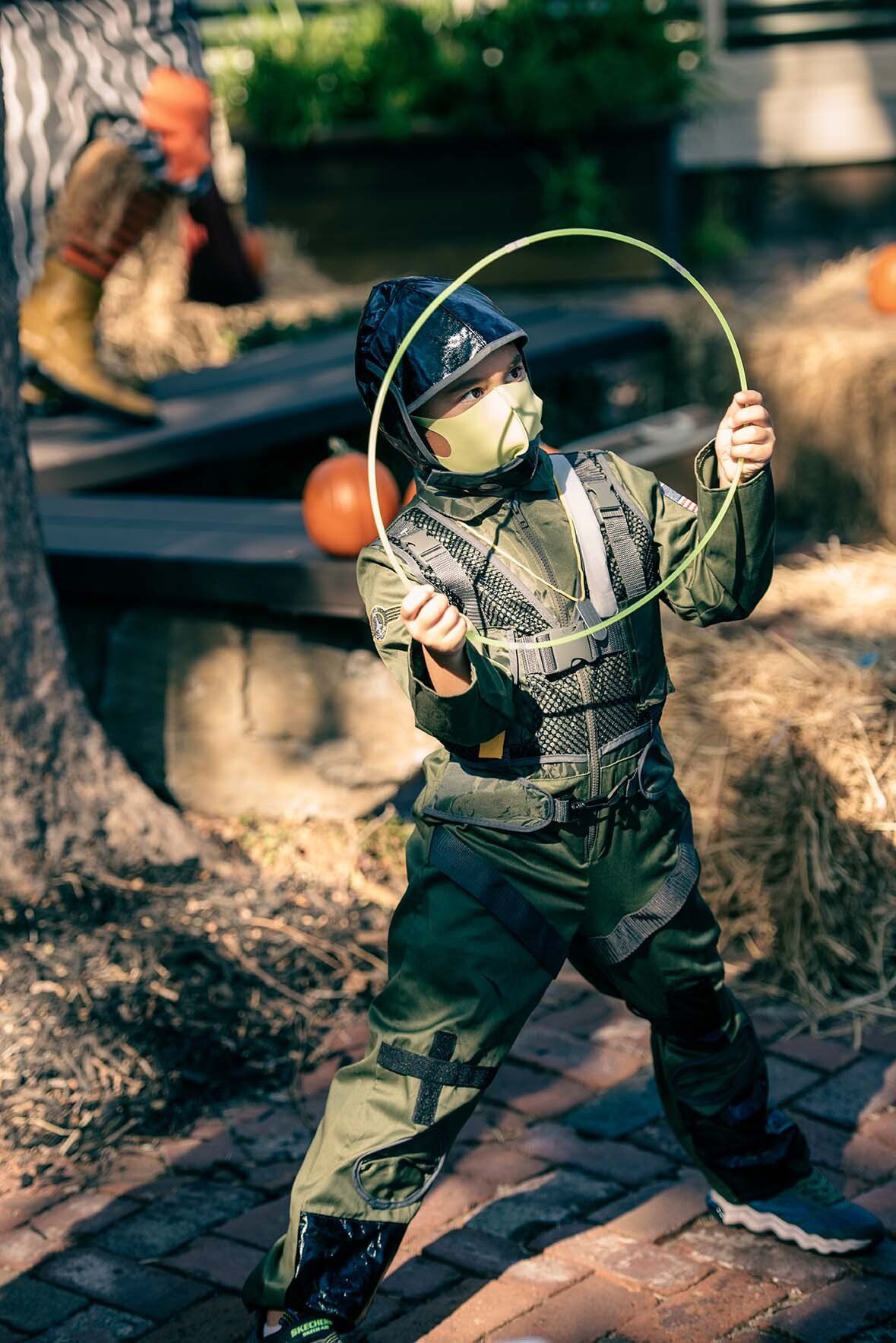 A young boy in a costume is playing with a hula hoop.