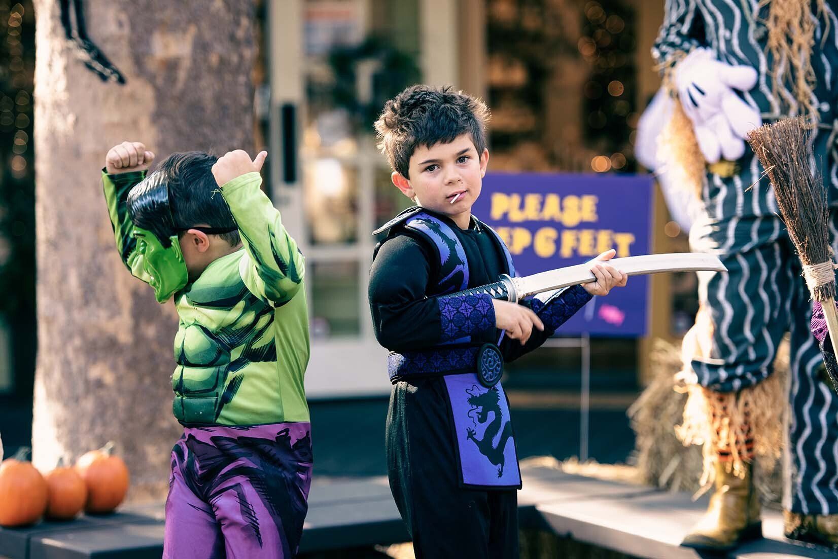 Two young boys in halloween costumes are standing next to each other on a stage.