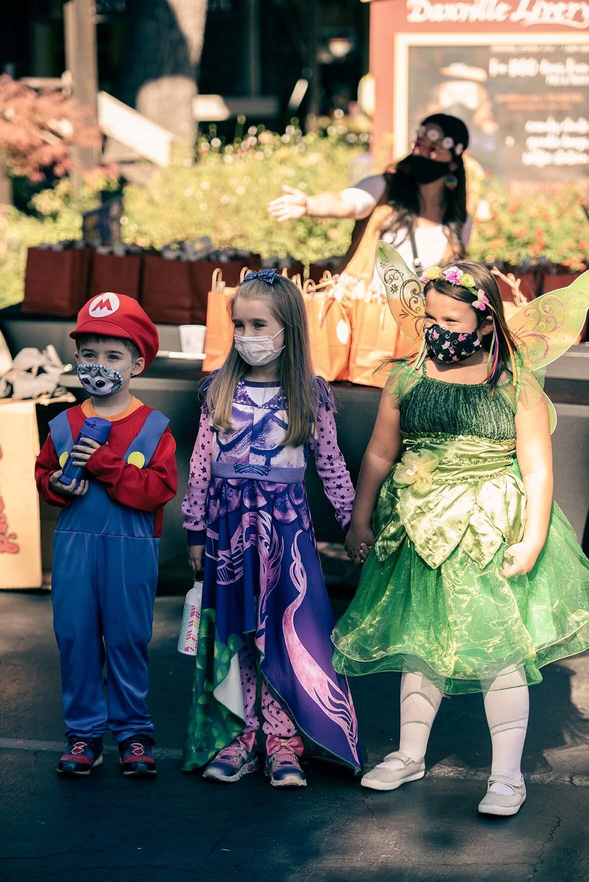 A group of children in halloween costumes are standing next to each other.