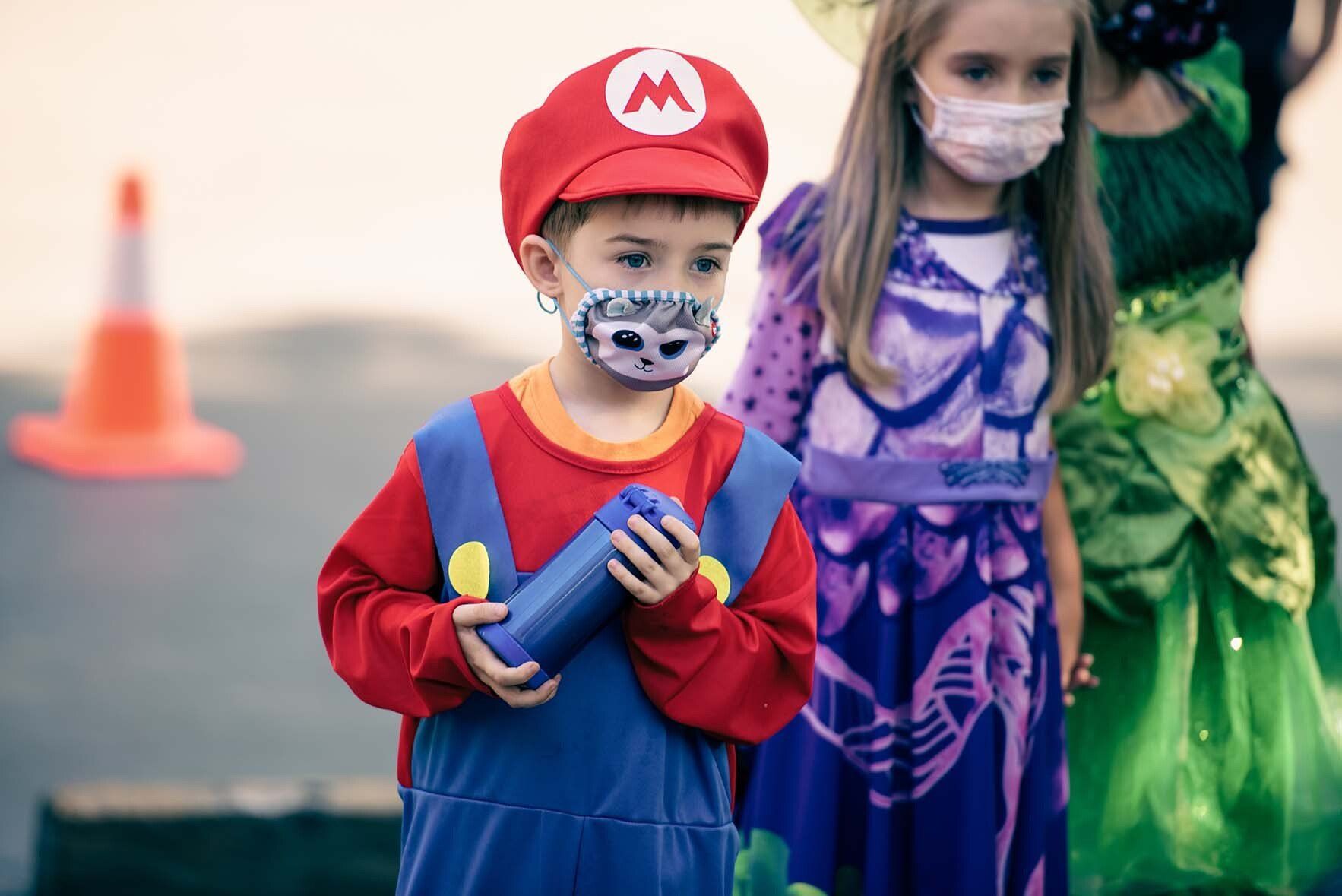 A boy in a mario costume is wearing a face mask.