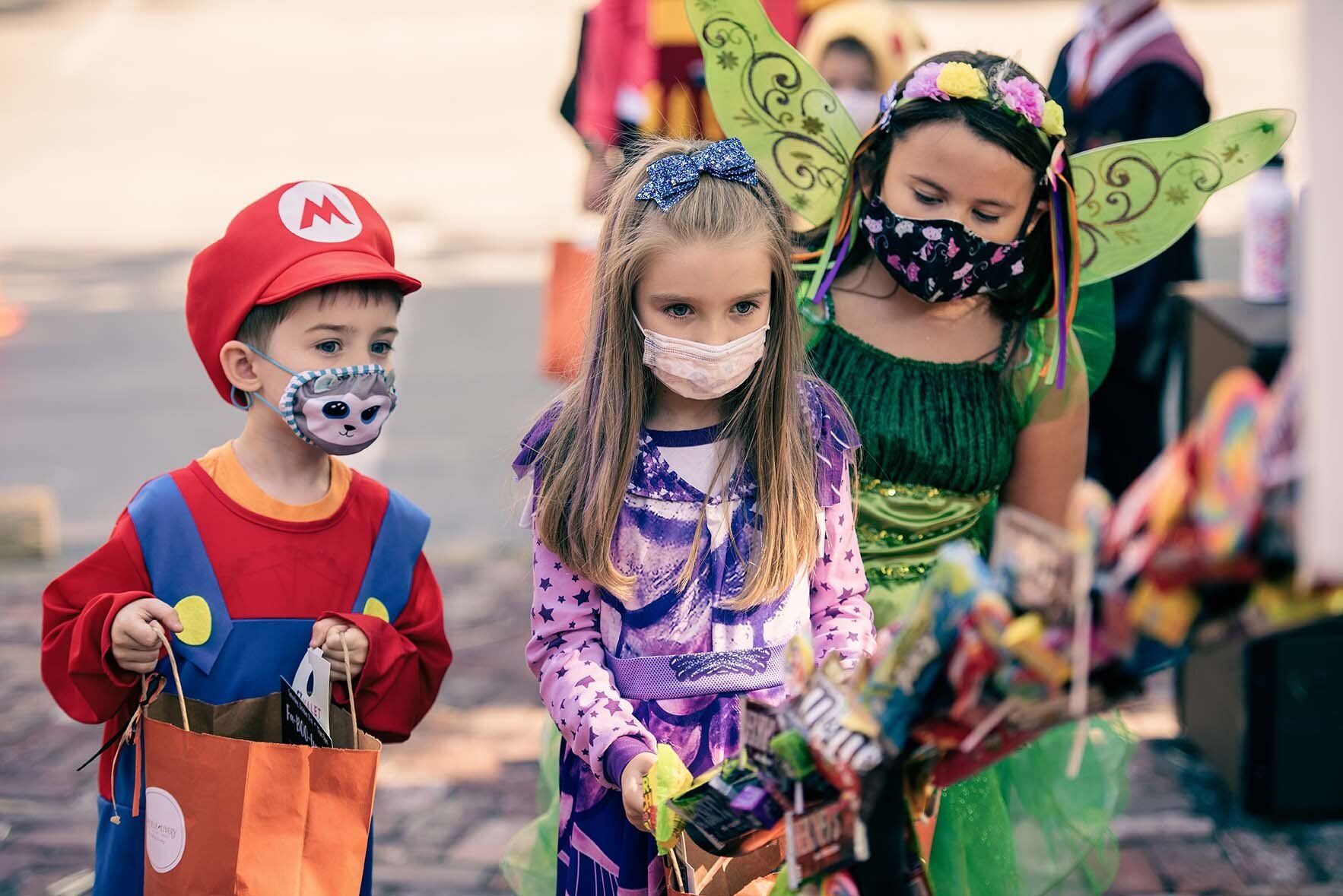 A group of children wearing masks are trick or treating.