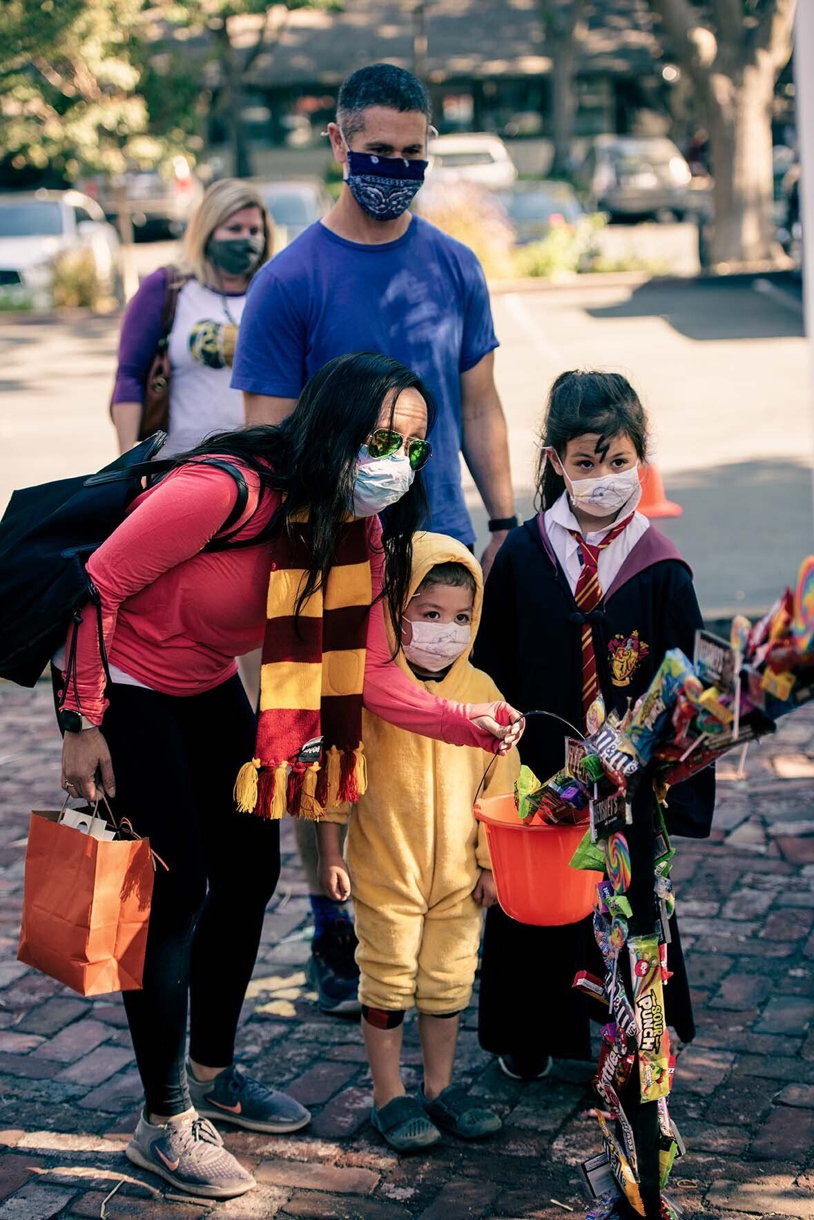 A group of people wearing face masks are trick or treating.