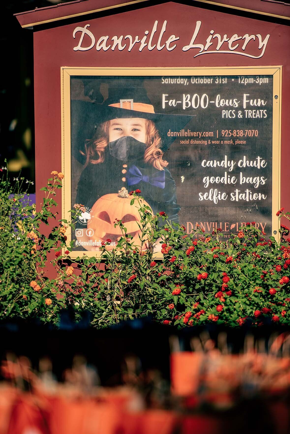 A sign with a picture of a girl wearing a mask and a pumpkin on it.