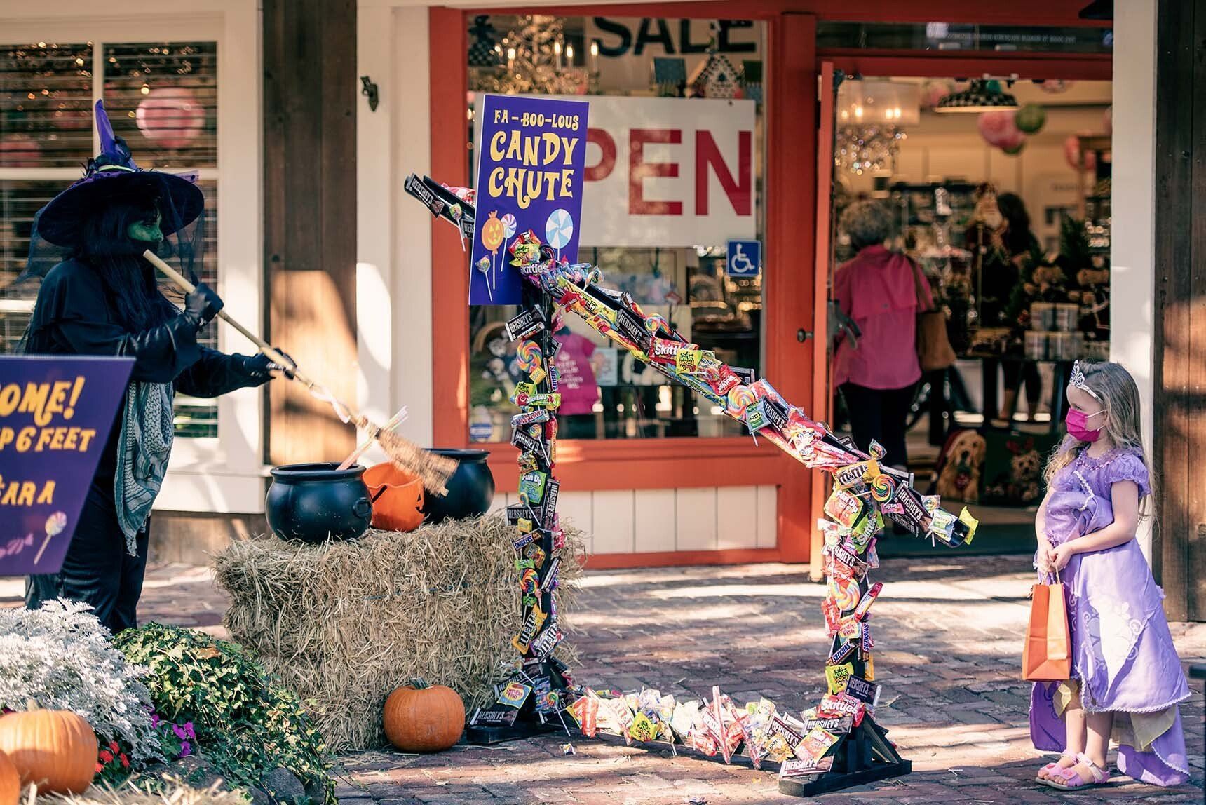 A little girl in a purple dress is standing in front of a store.