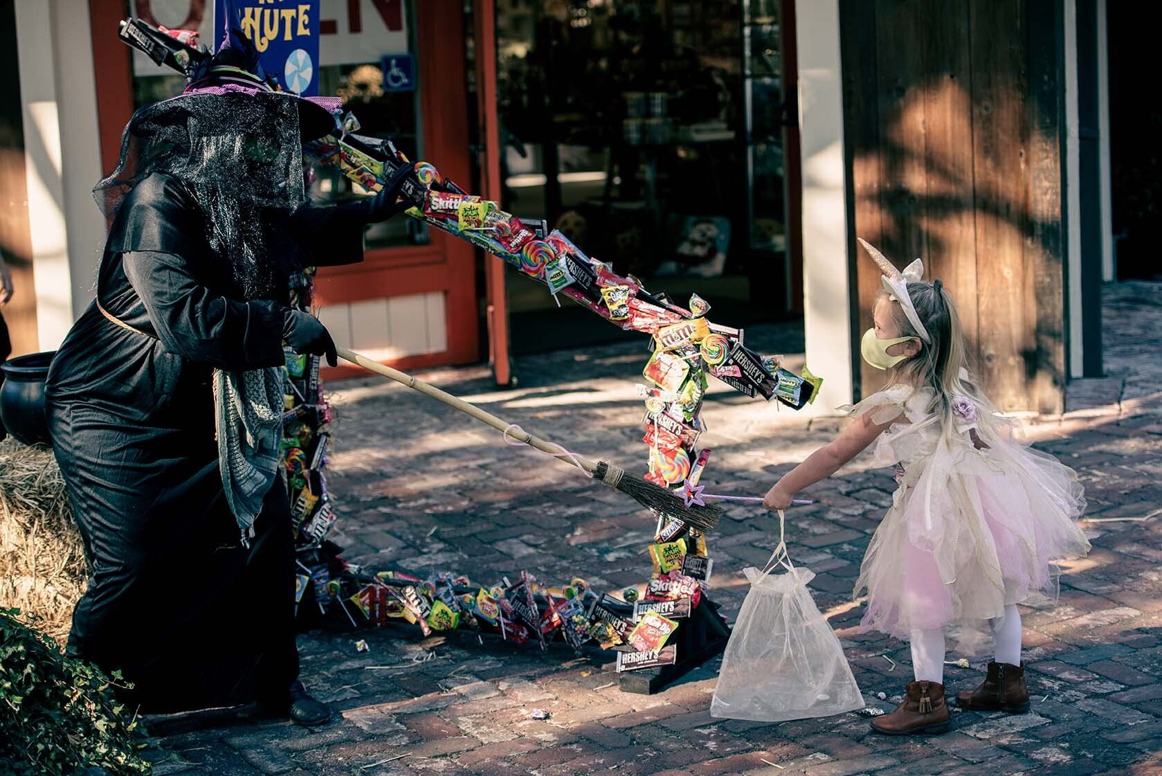 A little girl in a unicorn costume is standing next to a statue of a dragon.