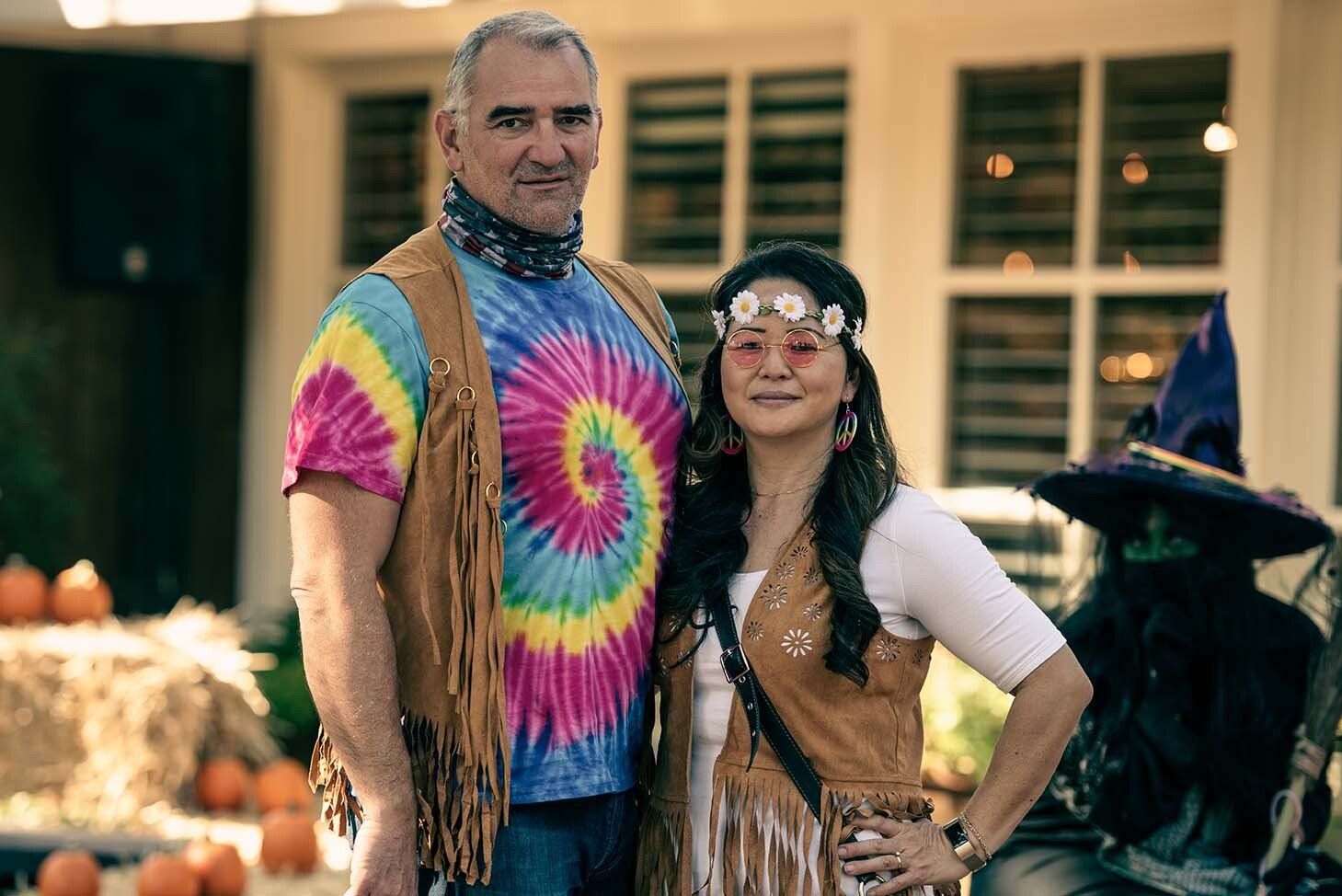 A man and a woman are posing for a picture in front of a house.