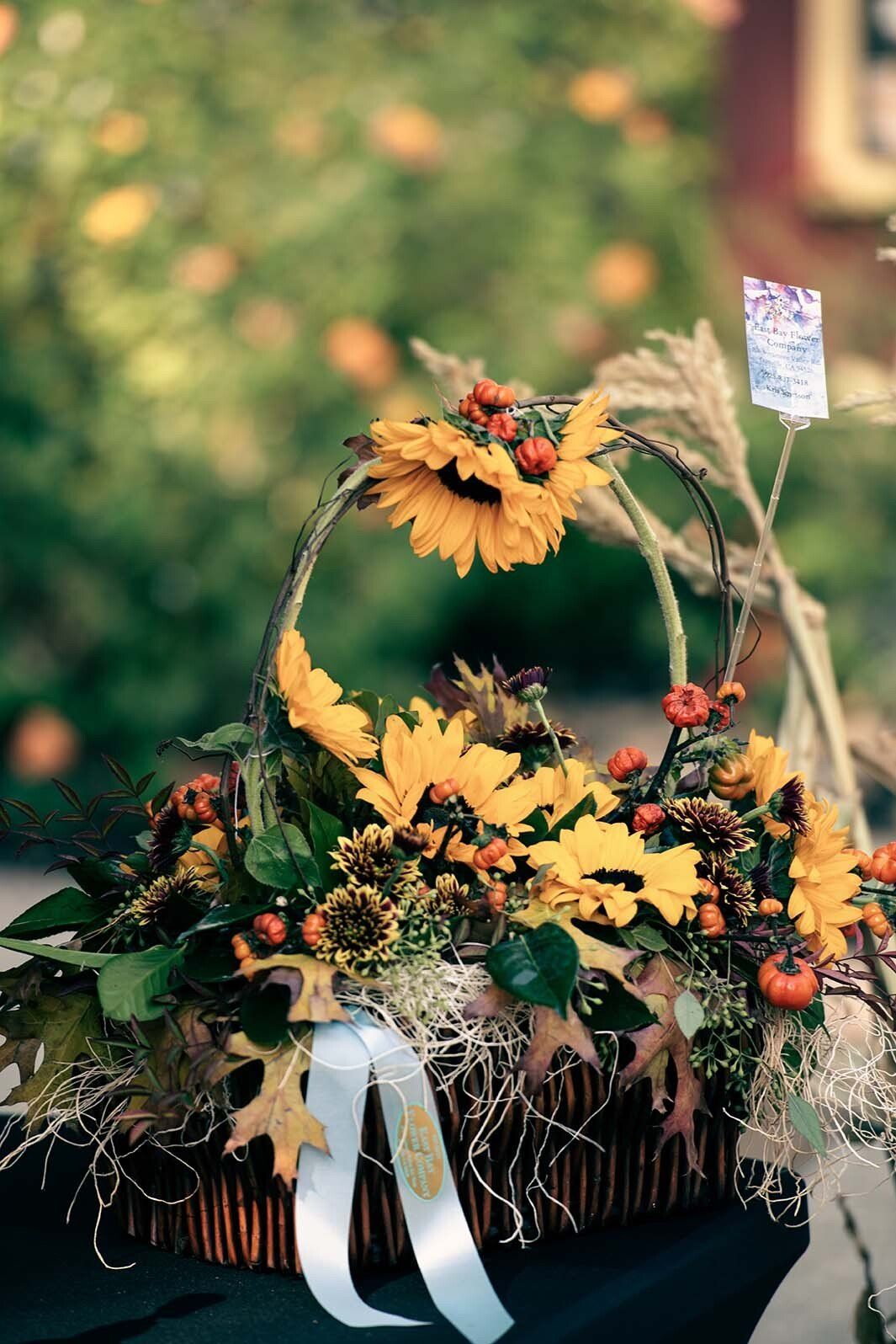 A basket filled with sunflowers and leaves is sitting on a table.