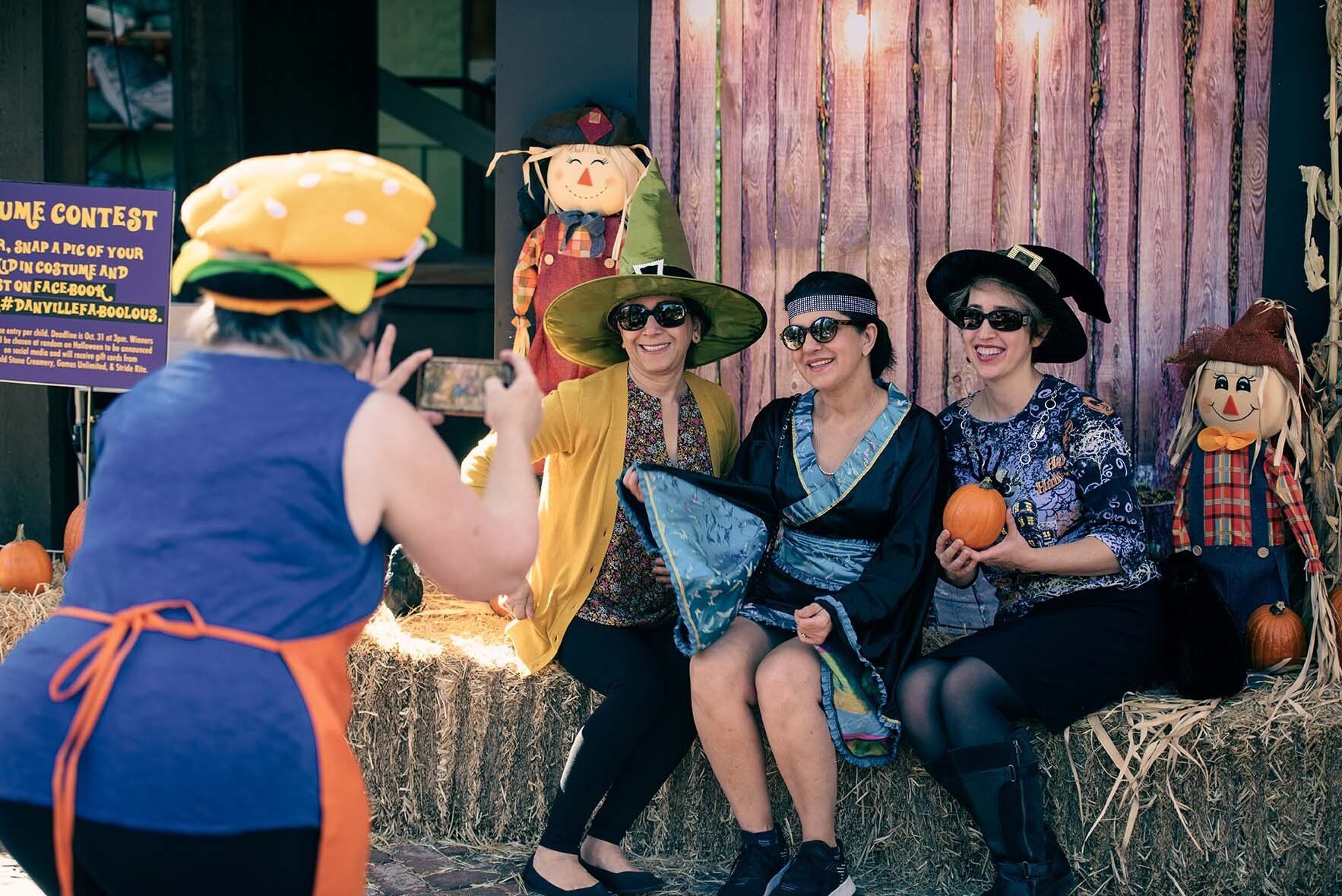 A woman is taking a picture of three women in halloween costumes.