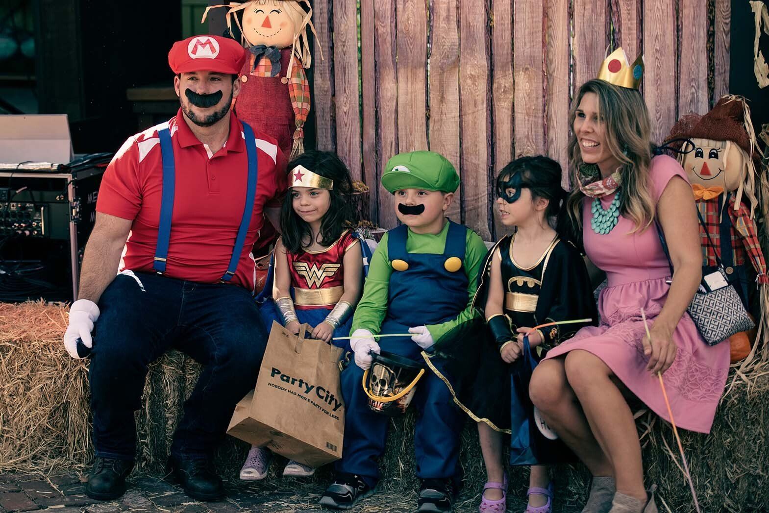 A group of people dressed in costumes are sitting on hay bales.