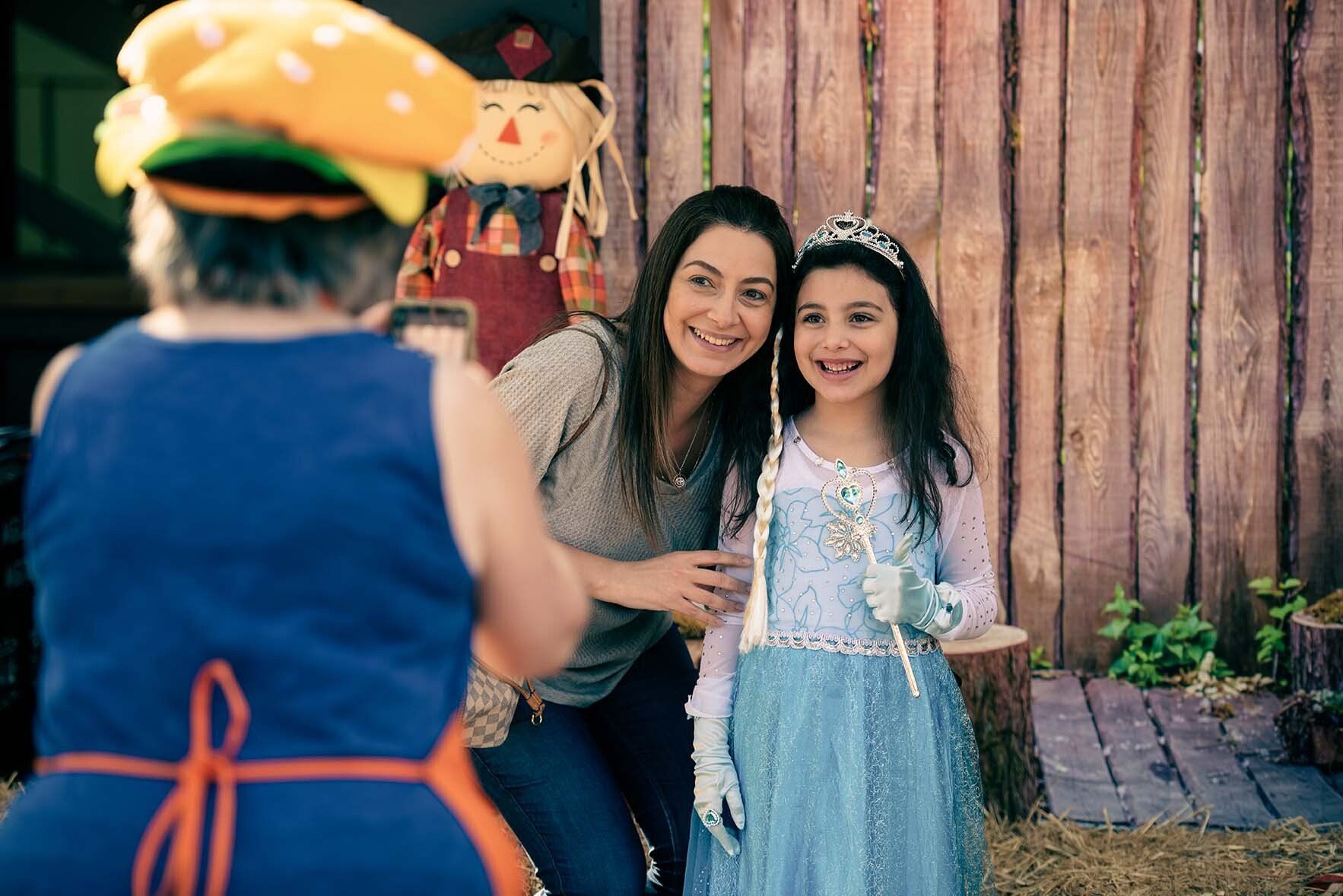A woman is taking a picture of a little girl in a princess dress.