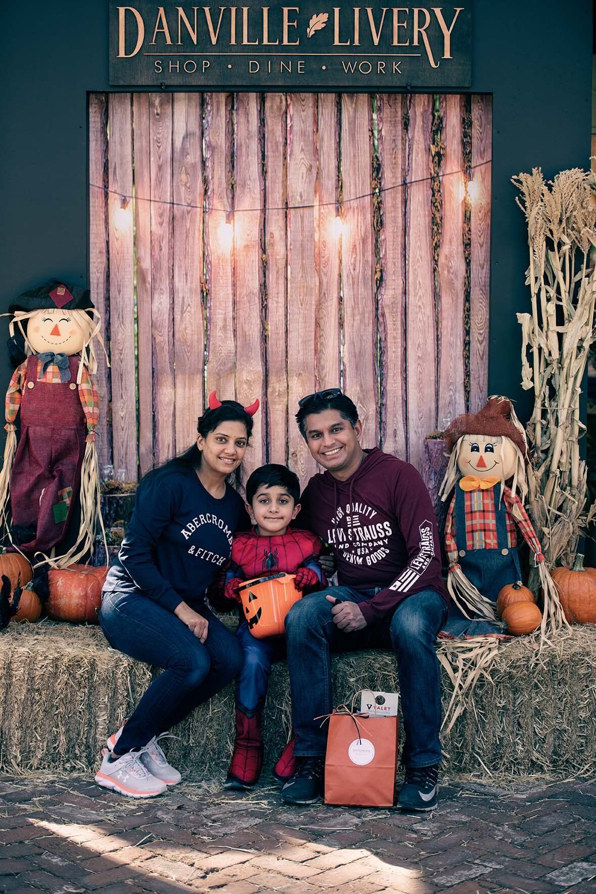 A family is posing for a picture while sitting on a hay bale.