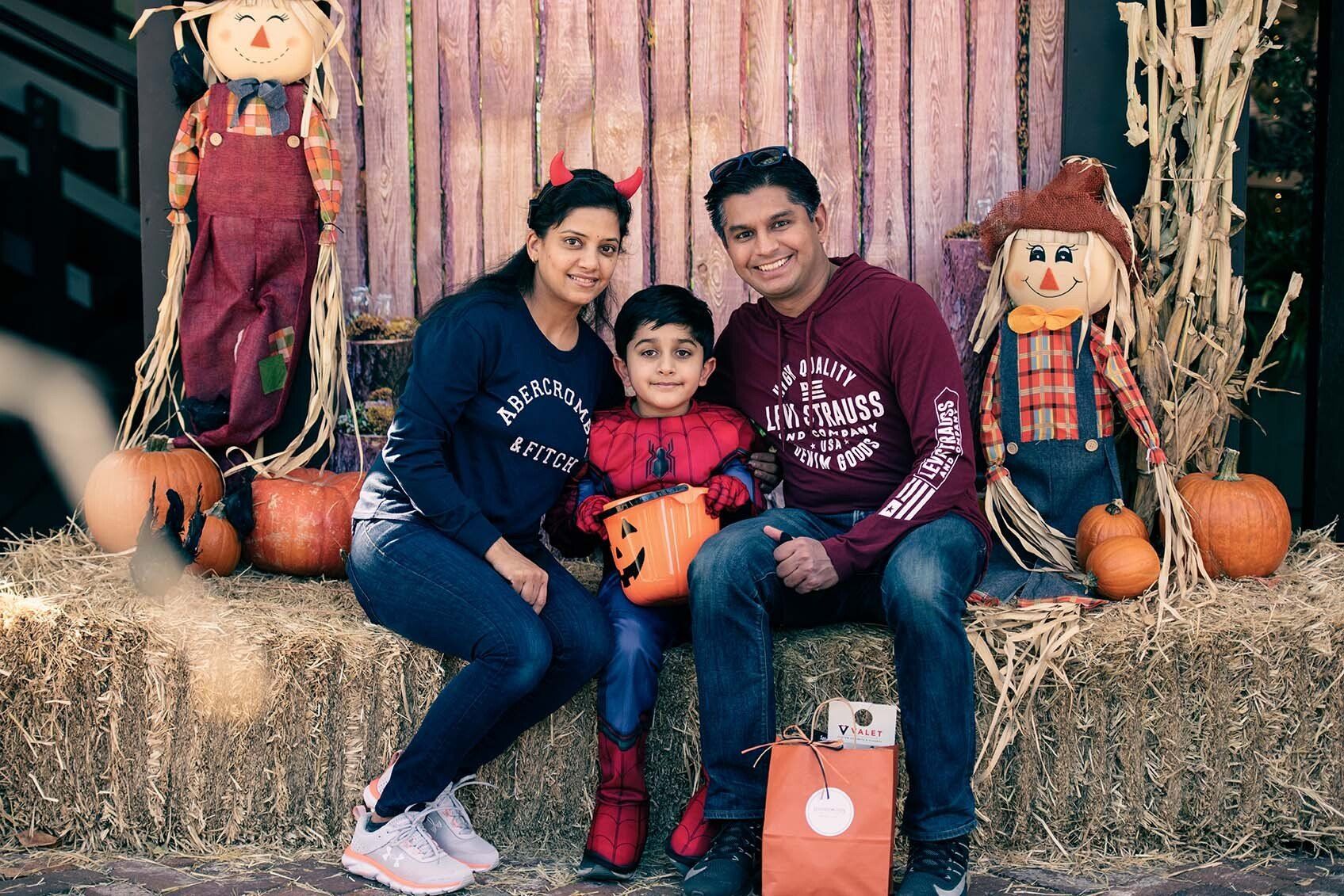 A family is posing for a picture while sitting on a hay bale.