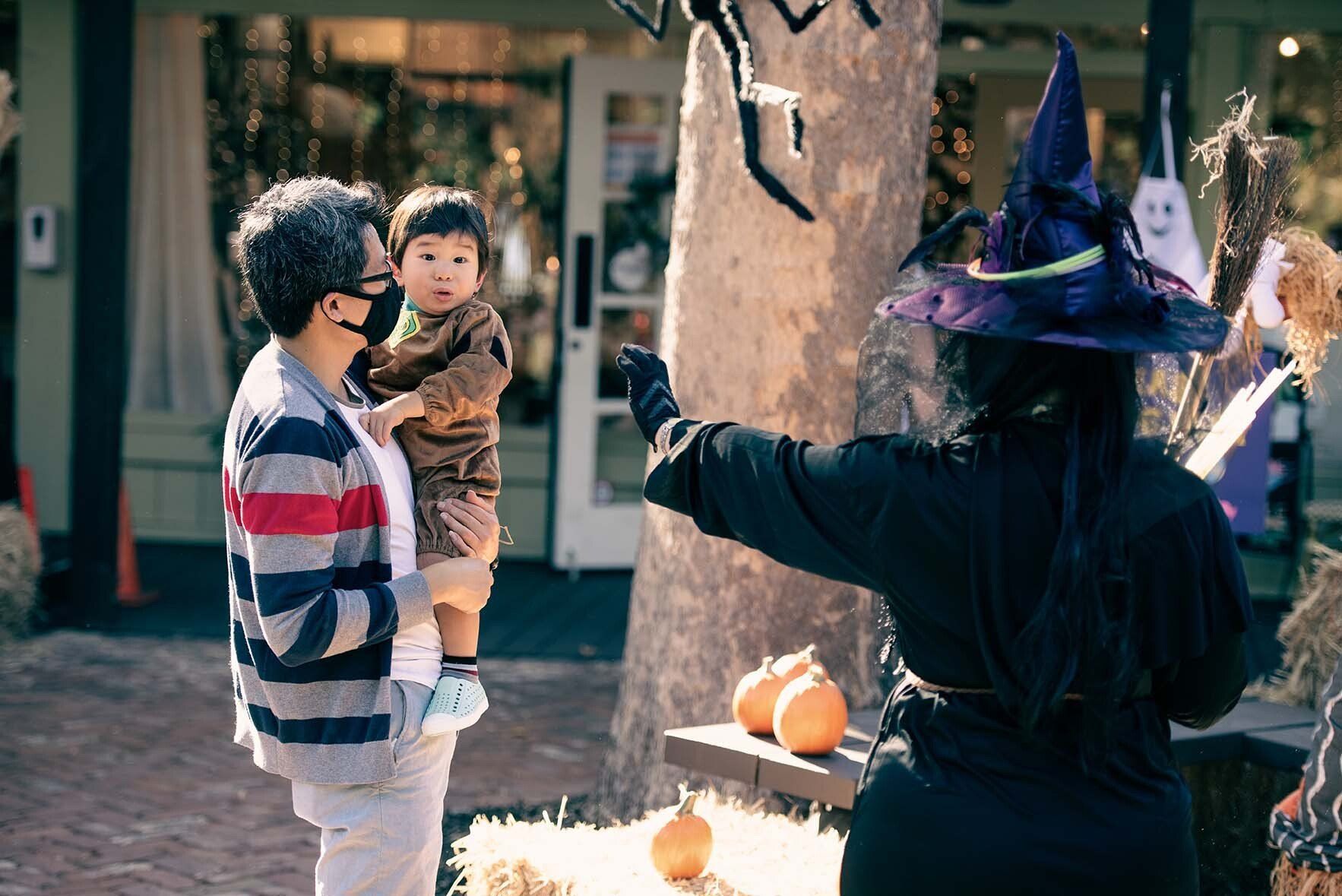 A woman in a witch costume is holding a baby.