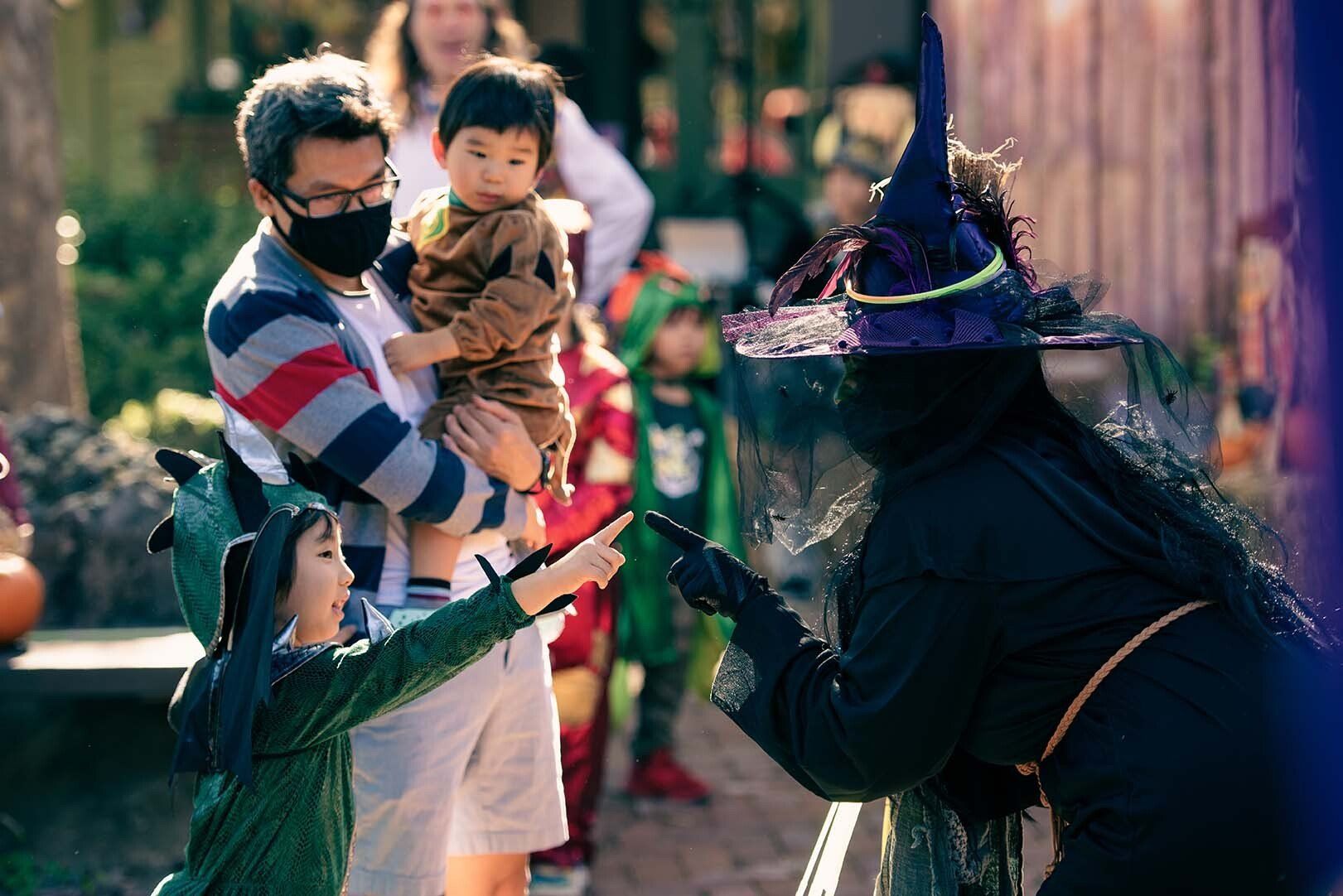 A woman in a witch costume is talking to a child.