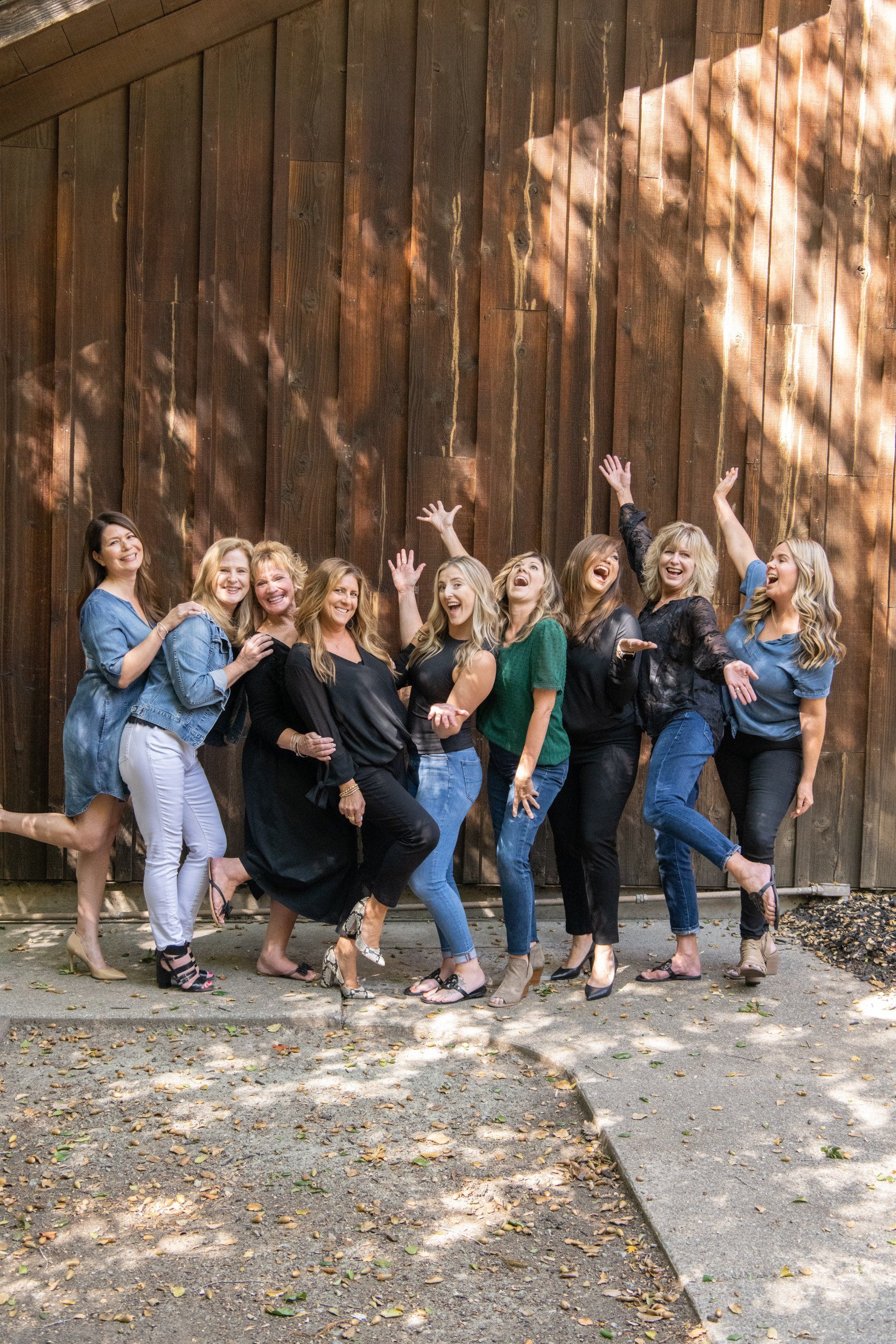A group of women are posing for a picture in front of a wooden wall.