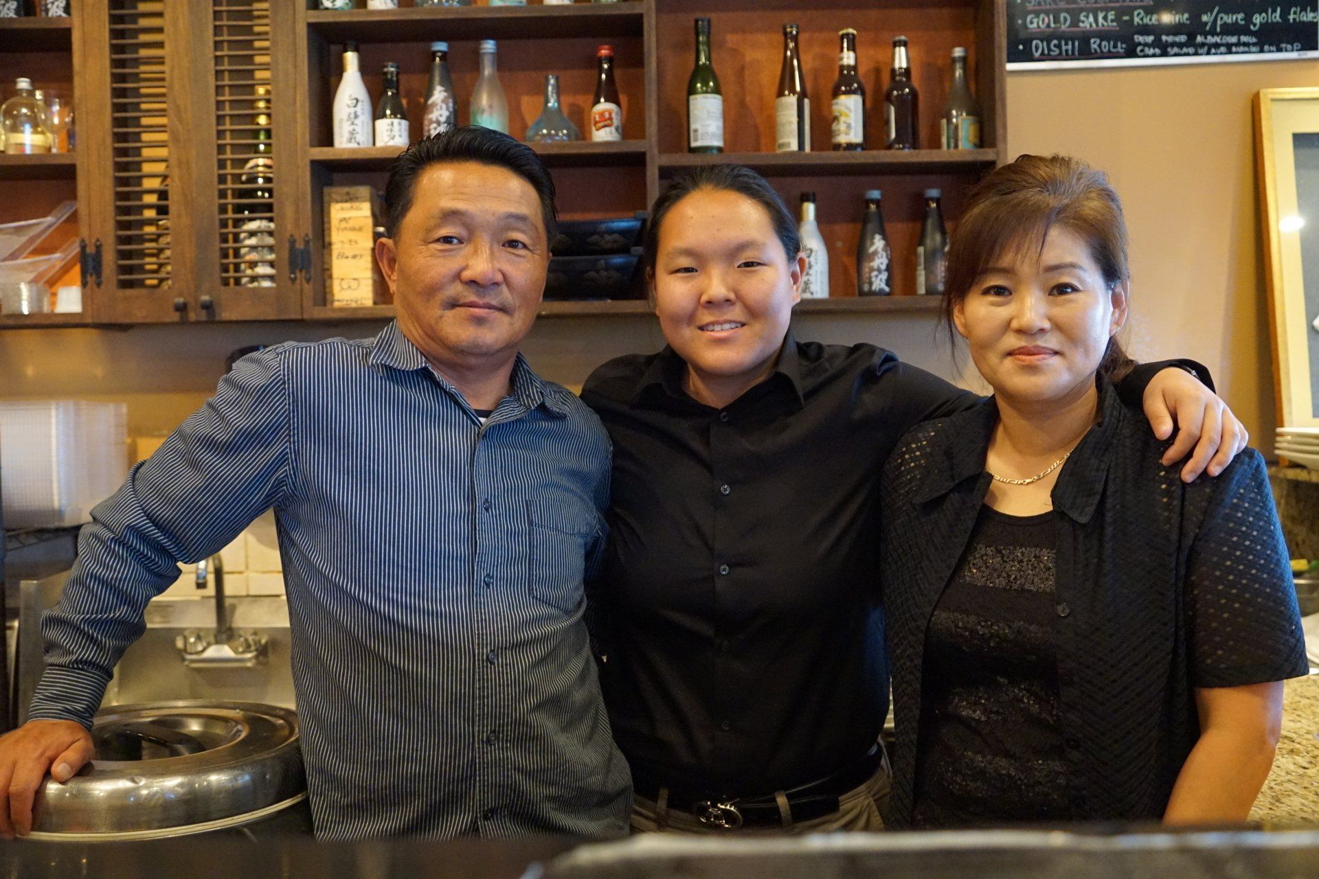 A man and two women posing for a picture in a kitchen