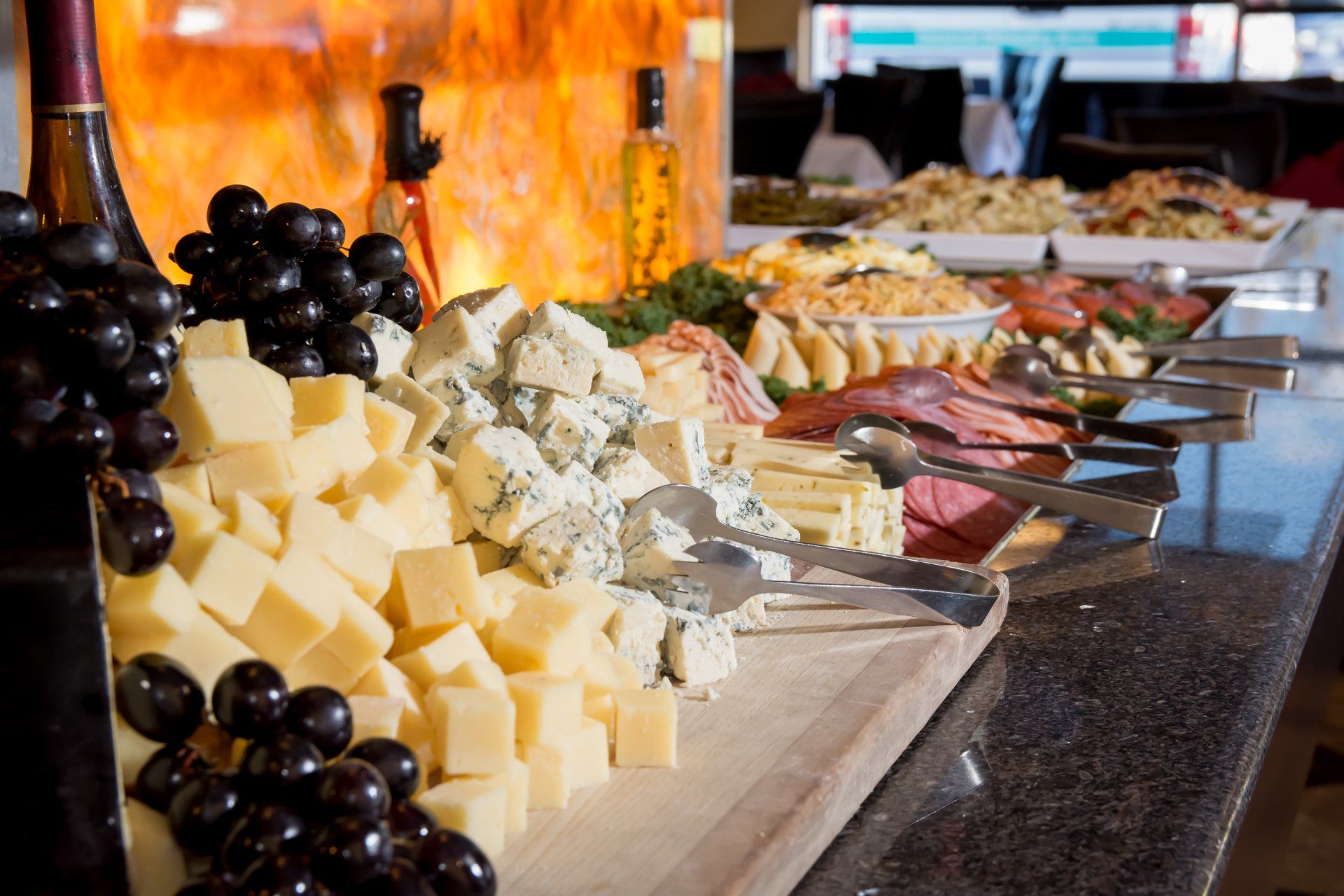 A buffet table with a variety of cheeses and grapes on it.