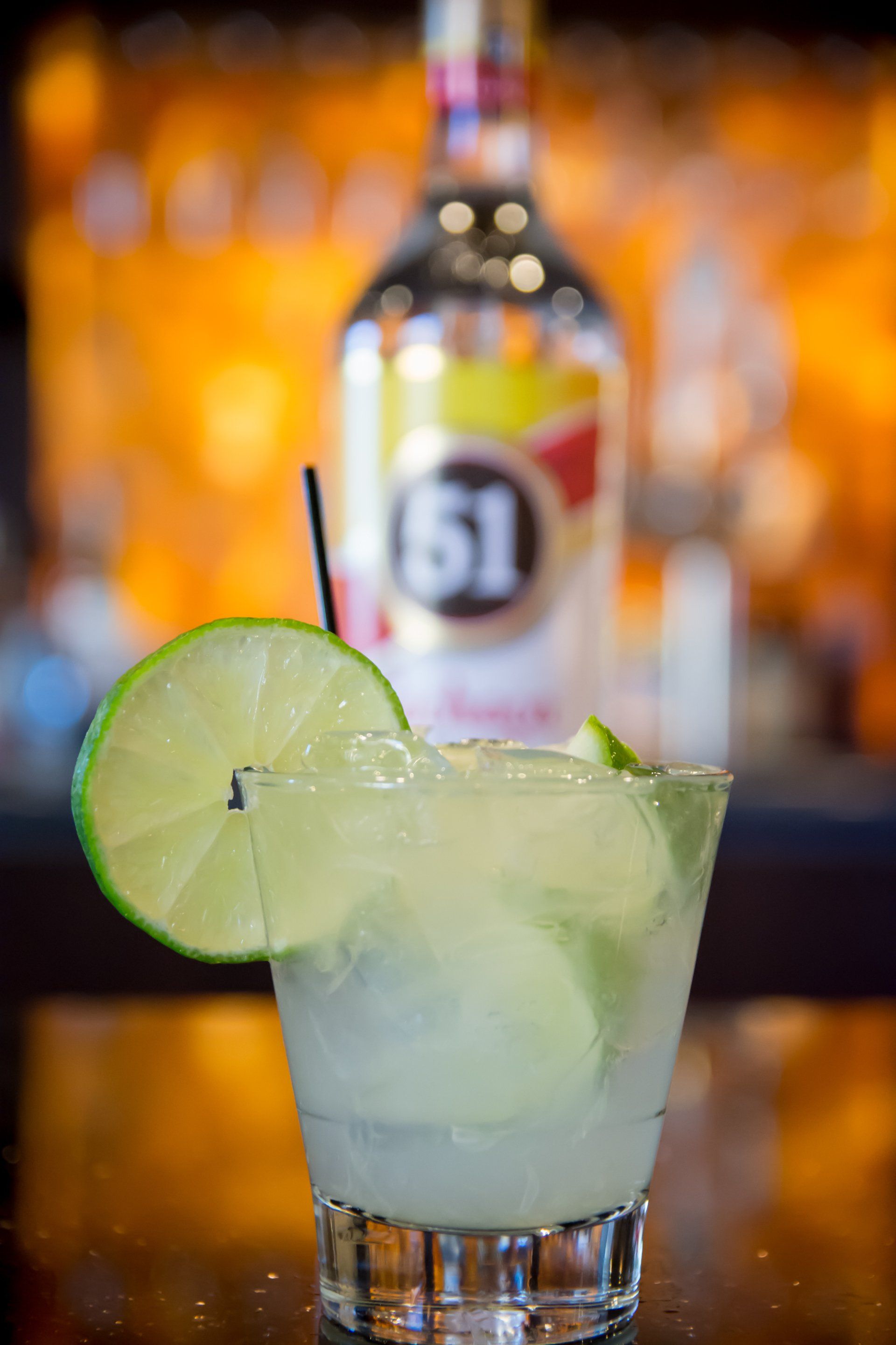 A close up of a drink with a bottle of alcohol in the background.