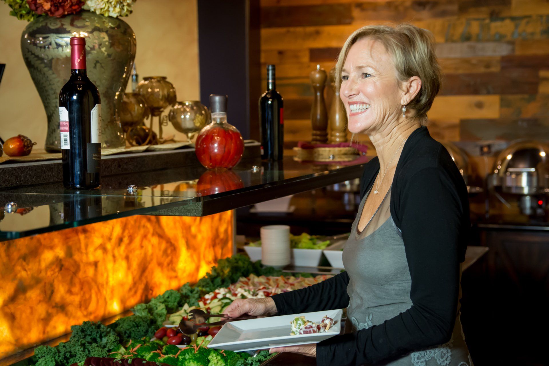 A woman is standing in front of a buffet line in a restaurant.