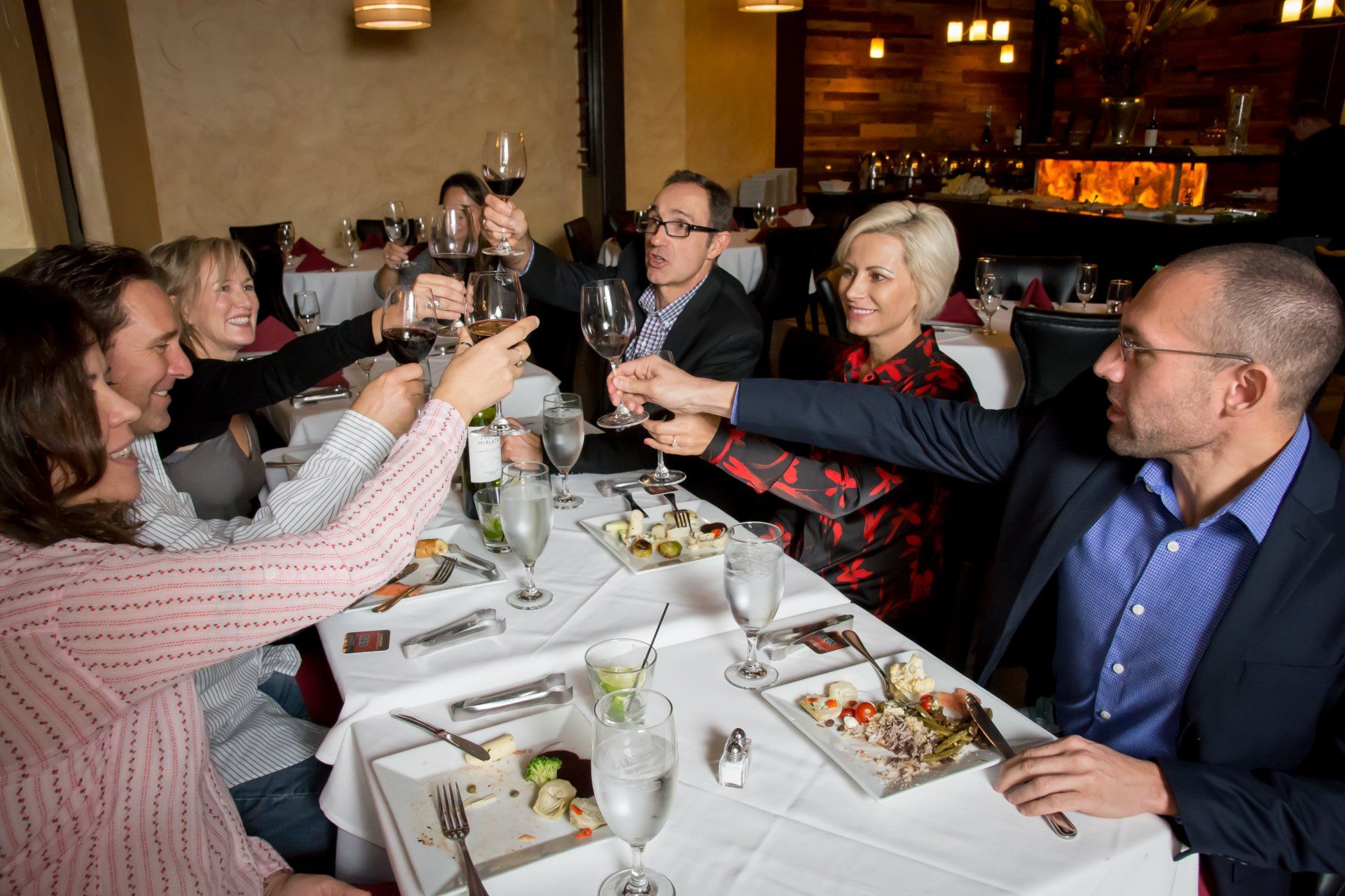A group of people are sitting at a table toasting with wine glasses.