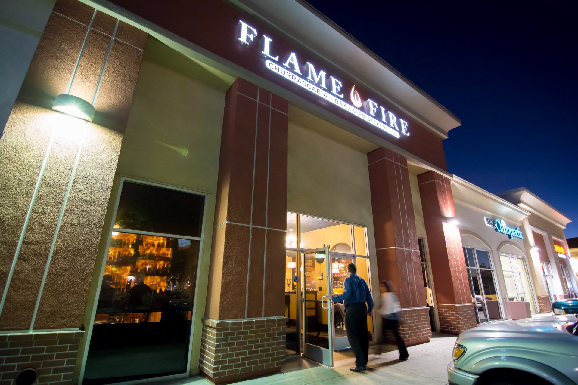 A flame & tire restaurant is lit up at night
