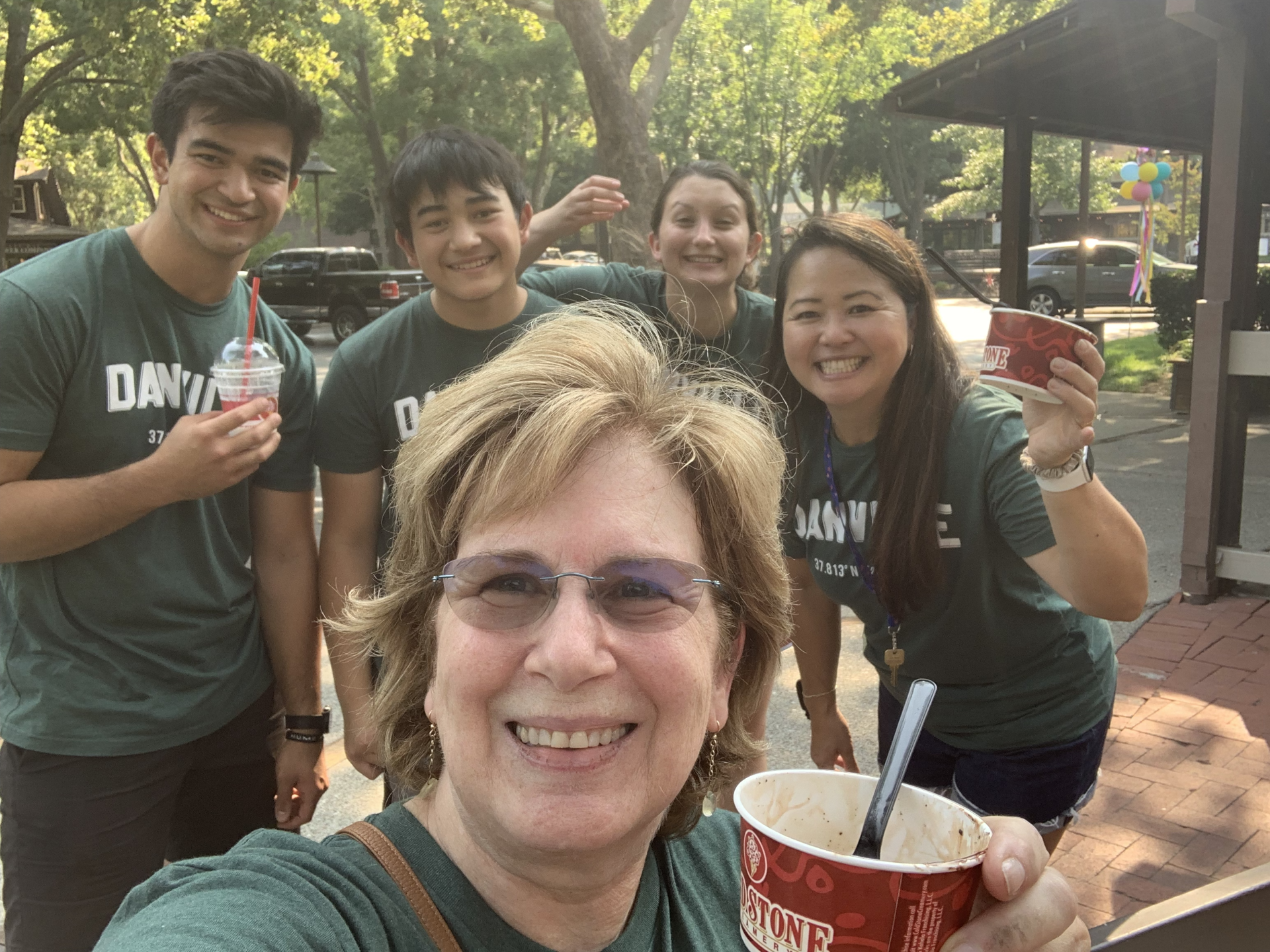 A group of people are posing for a picture and one of them is holding a cup of ice cream.