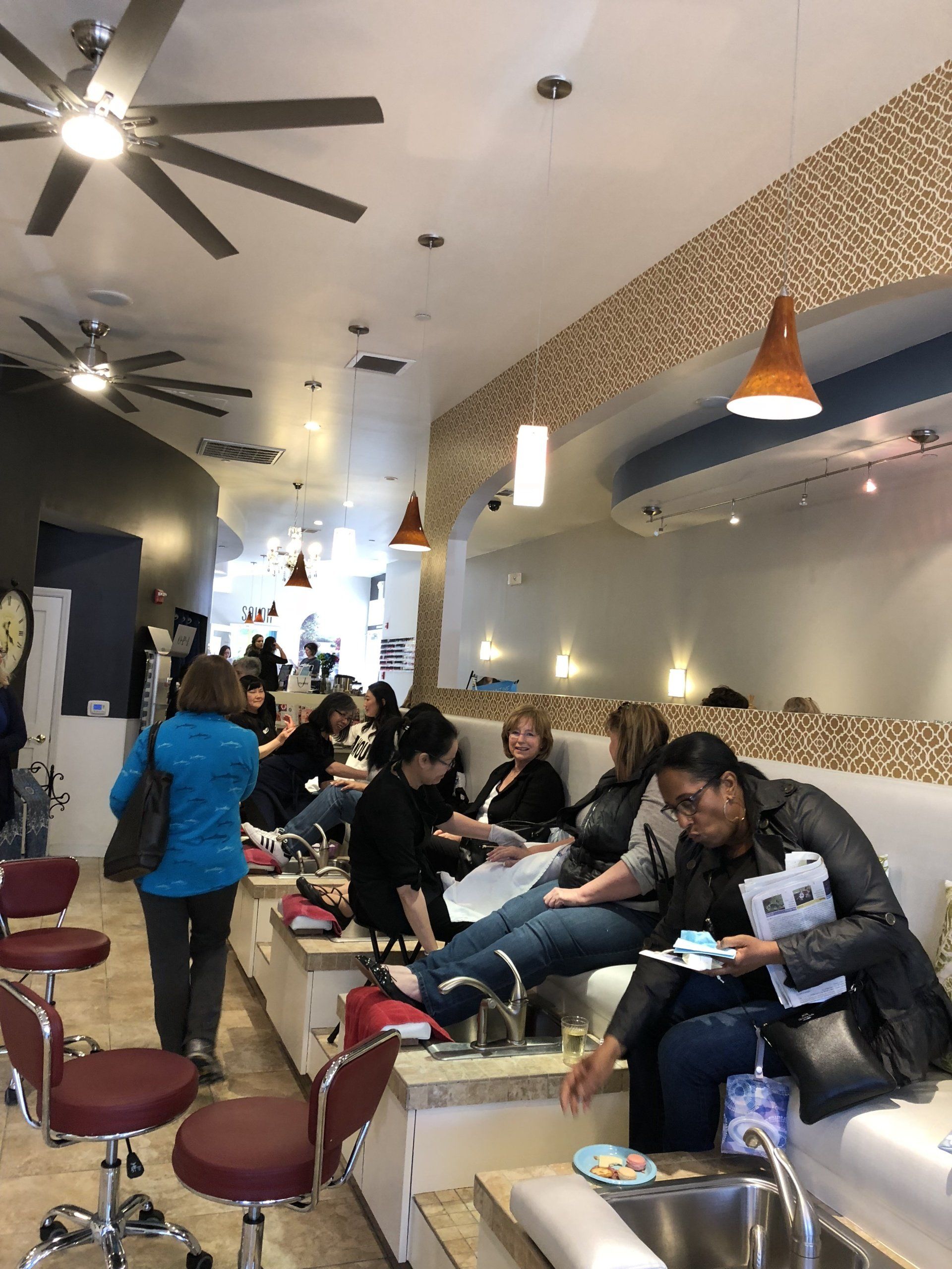 A group of people are sitting in a nail salon getting their nails done.