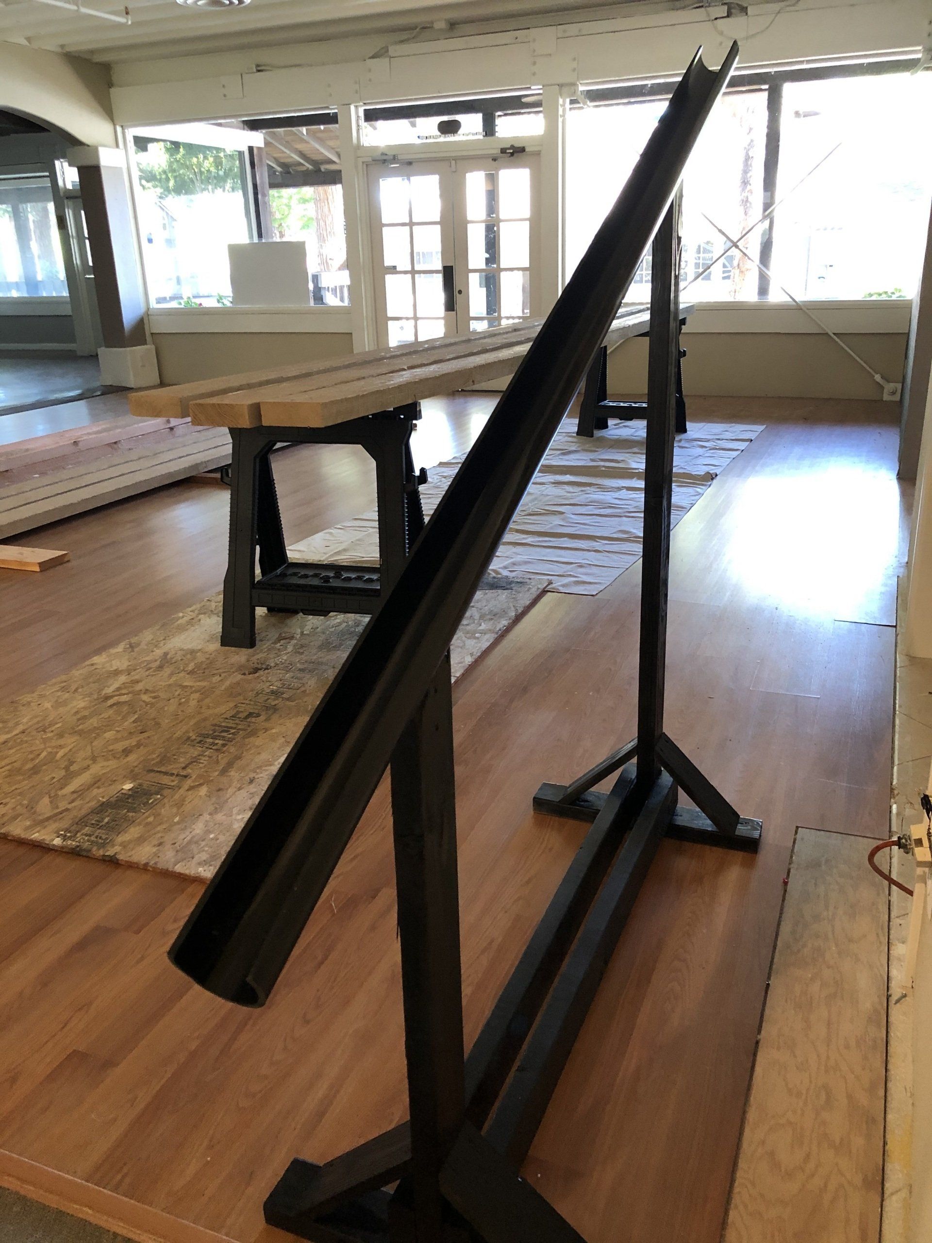 A large piece of metal is sitting on a wooden floor in a room.