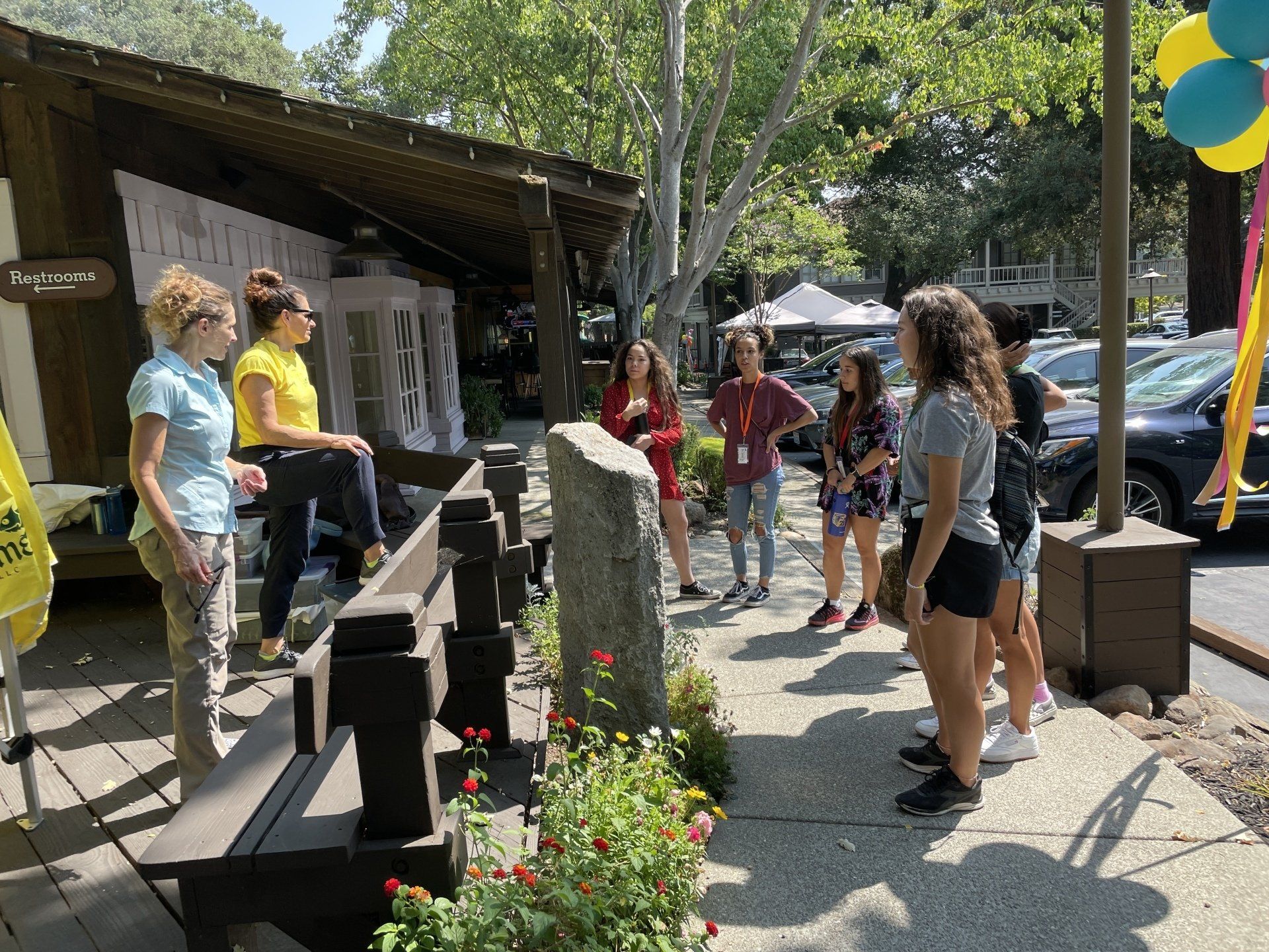 A group of people are standing on a sidewalk in front of a building.
