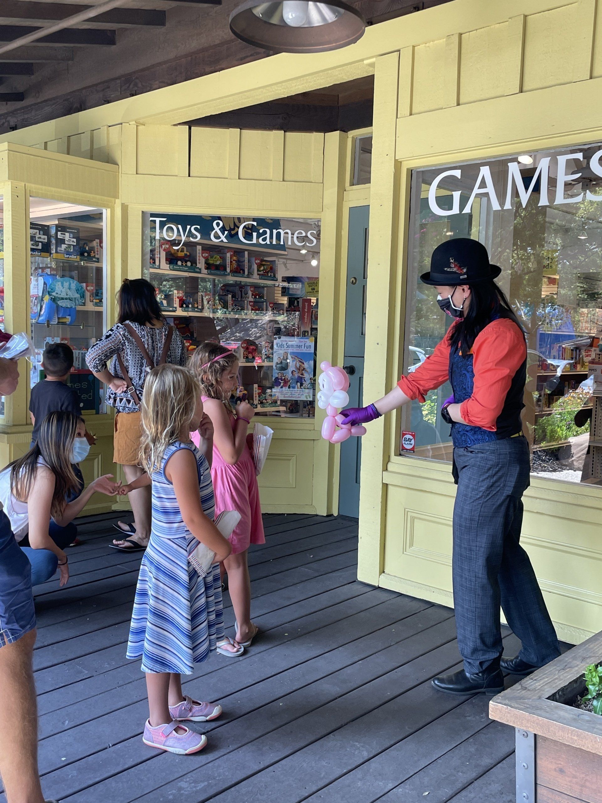 A man is holding a stuffed animal in front of a store called games