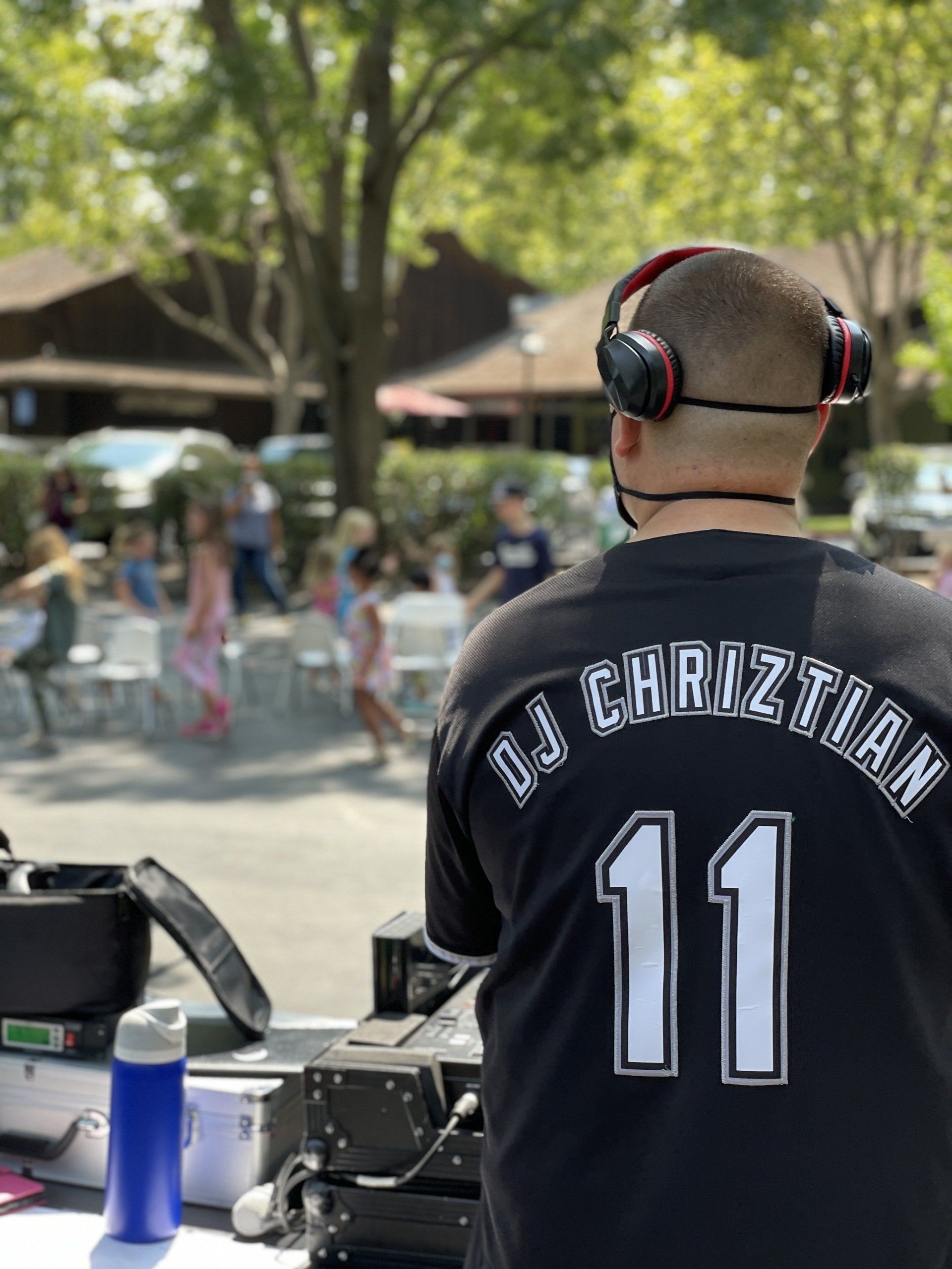 A dj is wearing headphones and a black shirt with the number 11 on it.