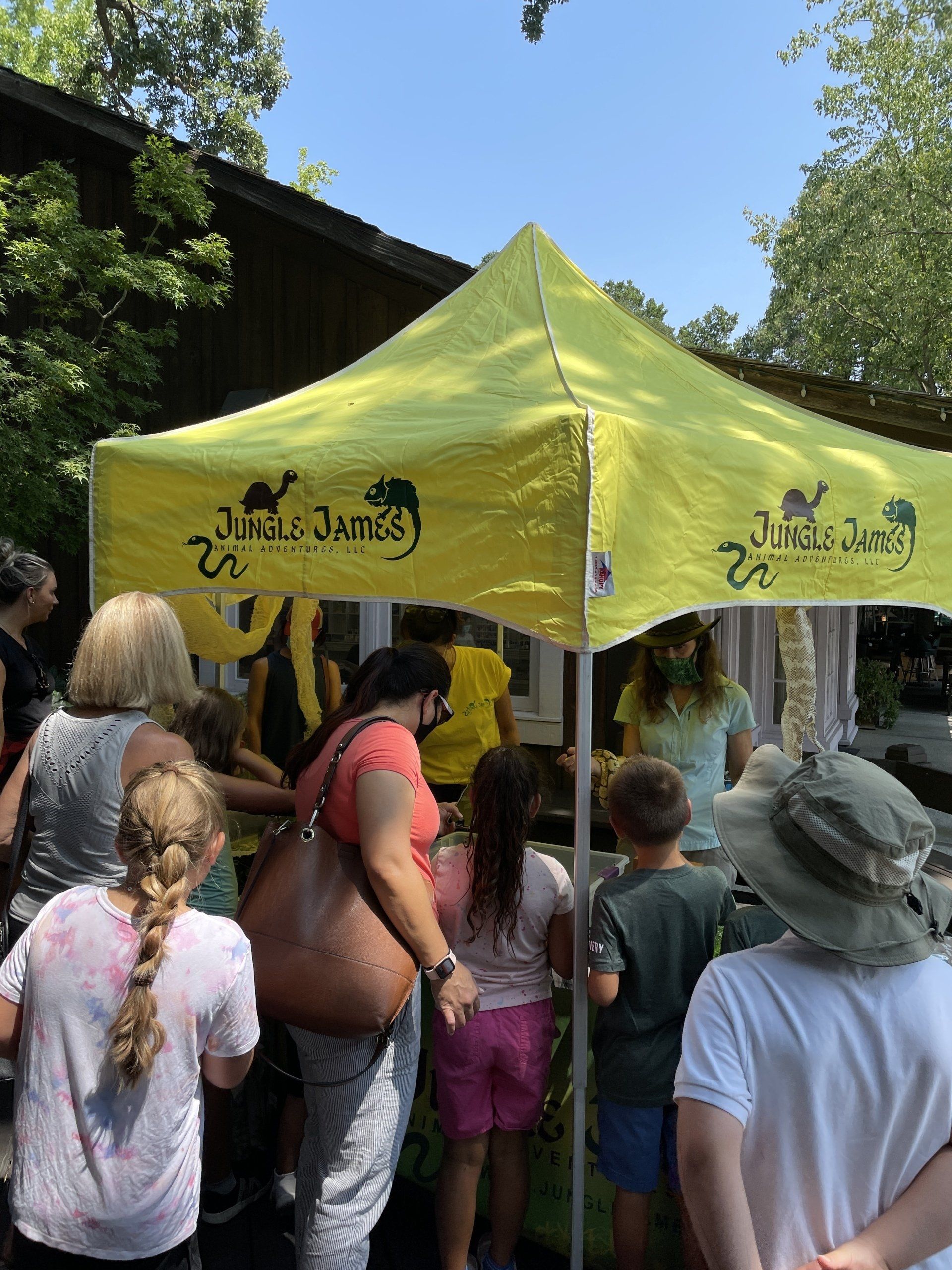 A group of people are standing under a yellow tent.