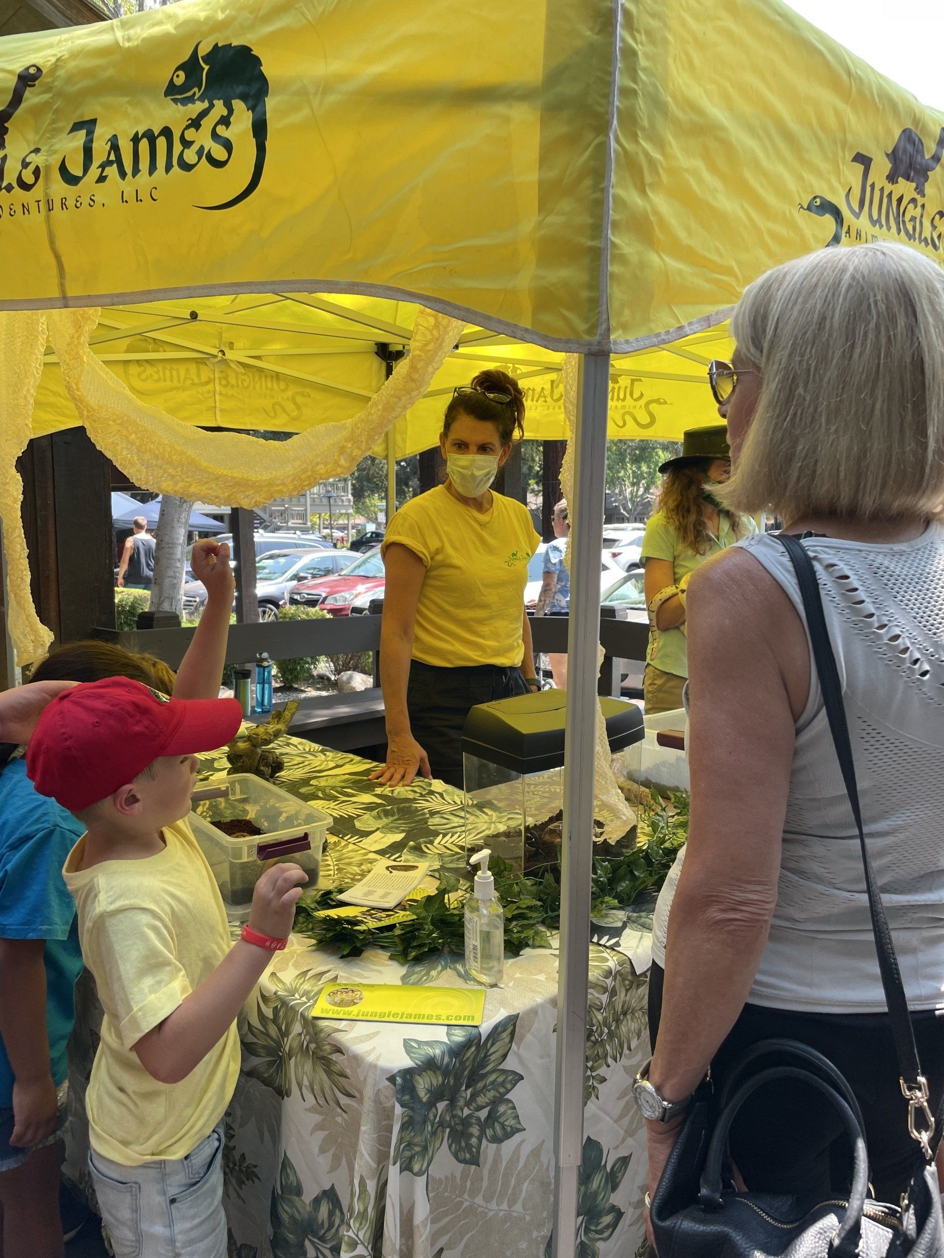 A group of people are standing under a yellow tent that says james