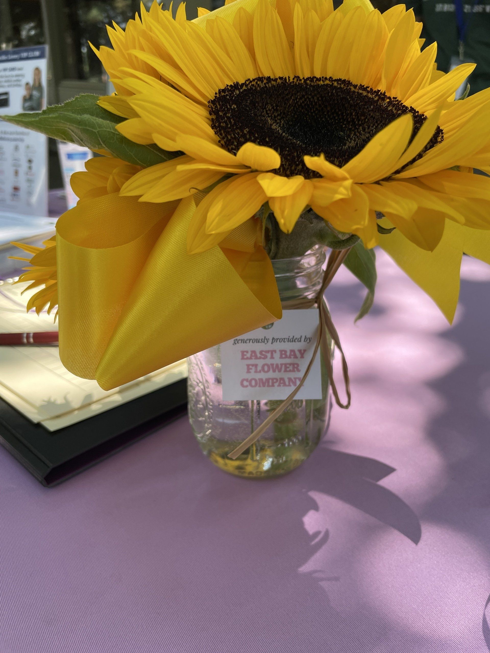 A sunflower in a jar that says east bay flower company